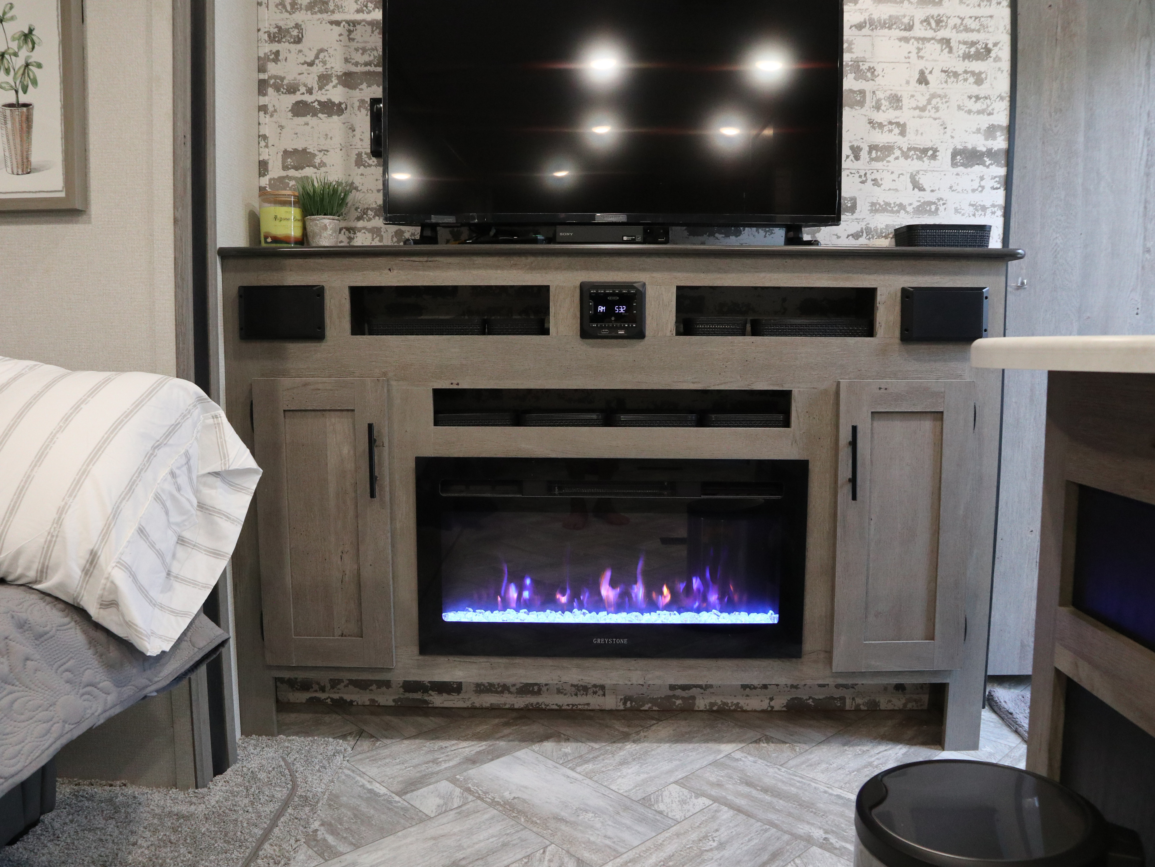 Inside a stylish RV rental: cozy entertainment center features TV & electric fireplace. Modern rustic interior.. Keystone Springdale 2021