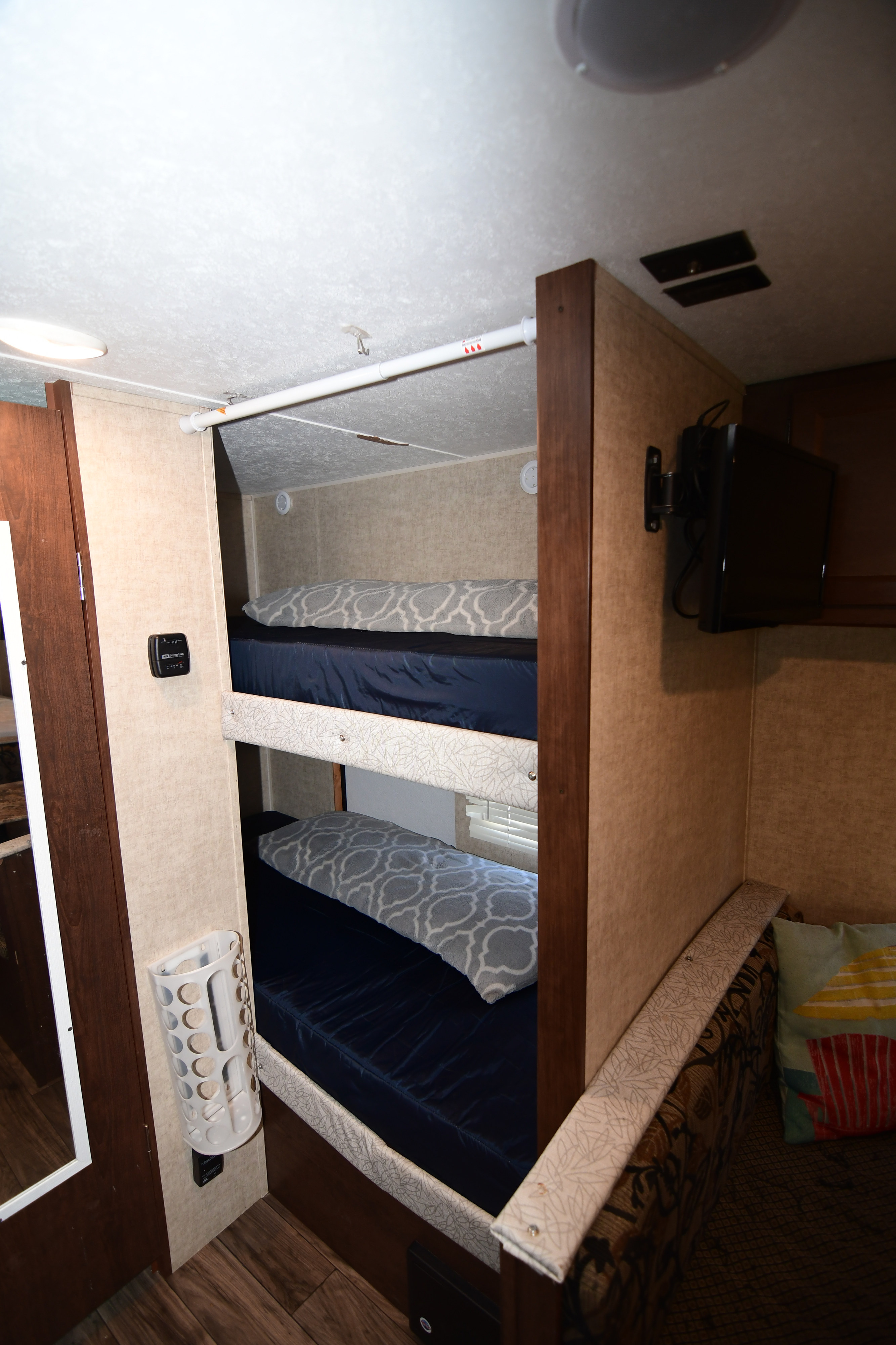 RV rental interior features cozy bunk beds with navy sheets and pillows, a thermostat, and a wall-mounted TV.. Keystone RV Hideout 2017