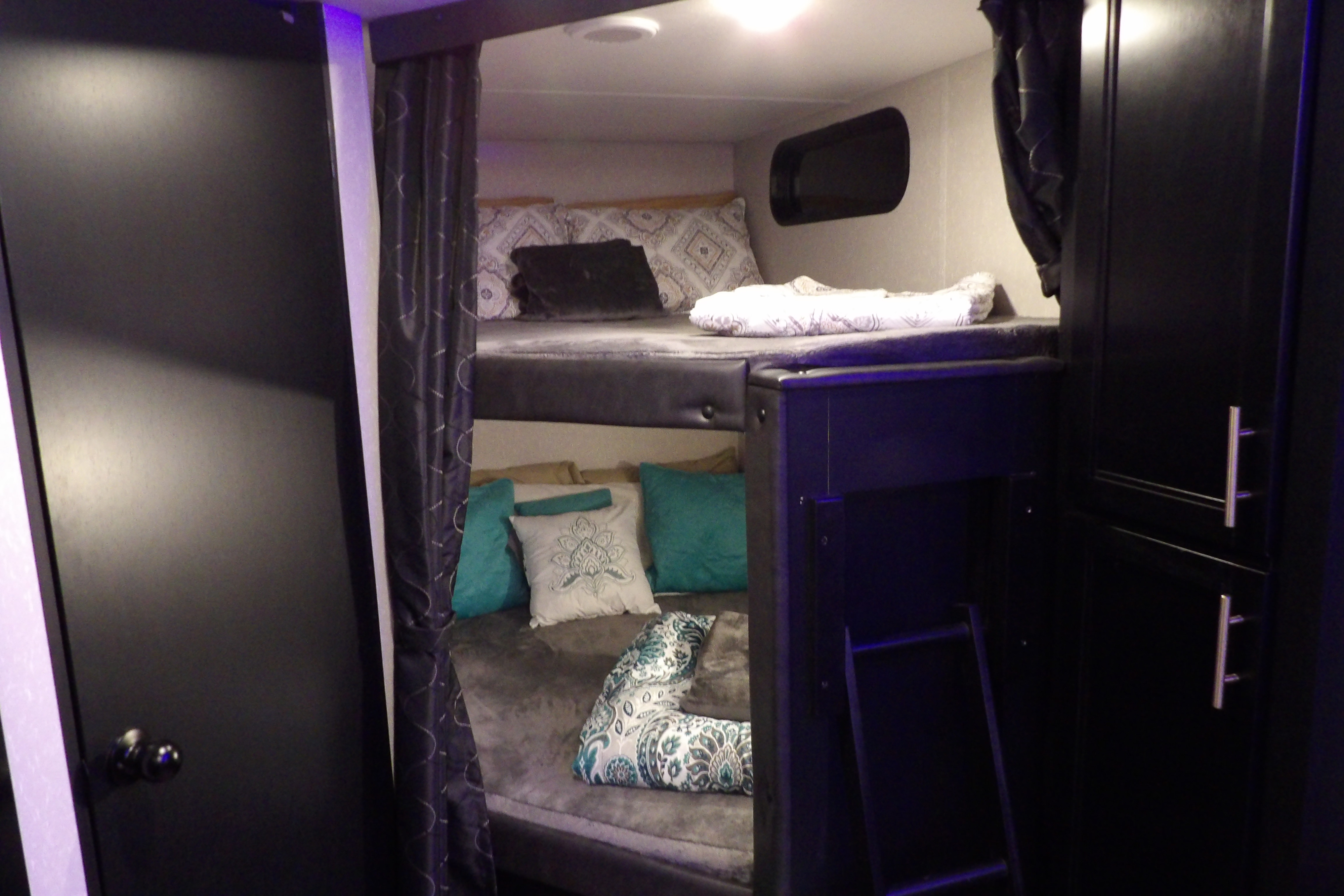 Comfortable bunk beds in this RV rental's interior, featuring privacy curtains, pillows, and storage.. Forest River Cherokee Grey Wolf 2021