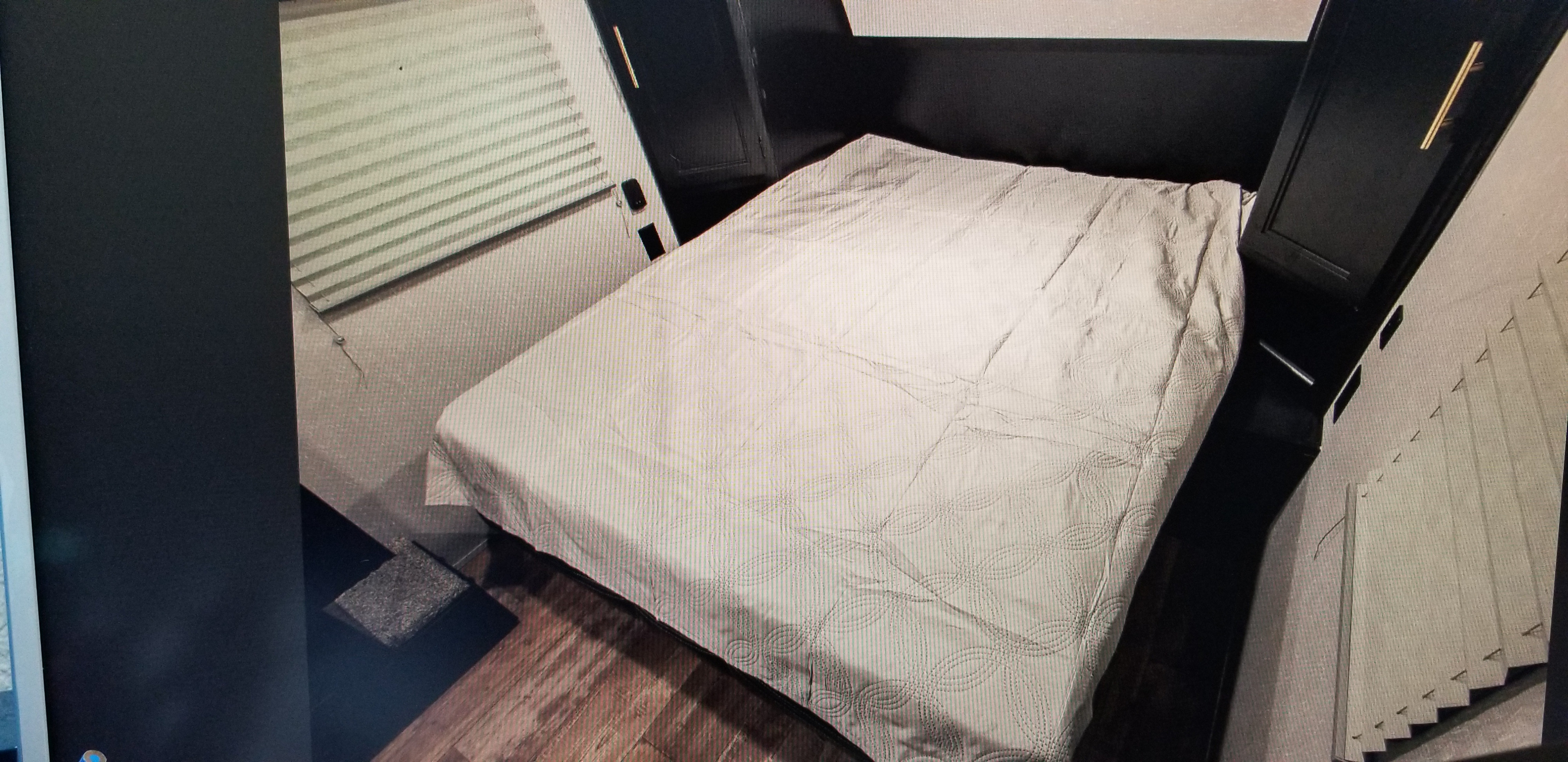 Inside an RV rental, a compact bedroom features a neatly made bed, dark storage cabinets, and window blinds.. Forest River Cherokee Wolf Pup 2021