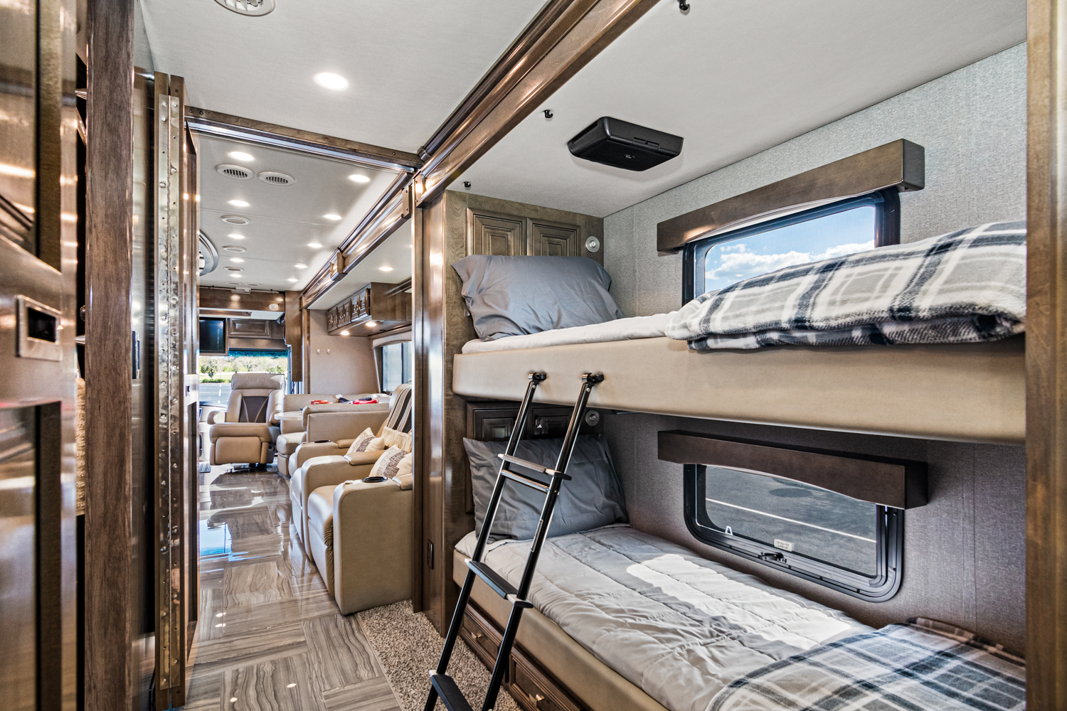 Modern RV rental with bunk beds, cozy bedding, and a spacious living area beyond.. Fleetwood Discovery LXE 2020