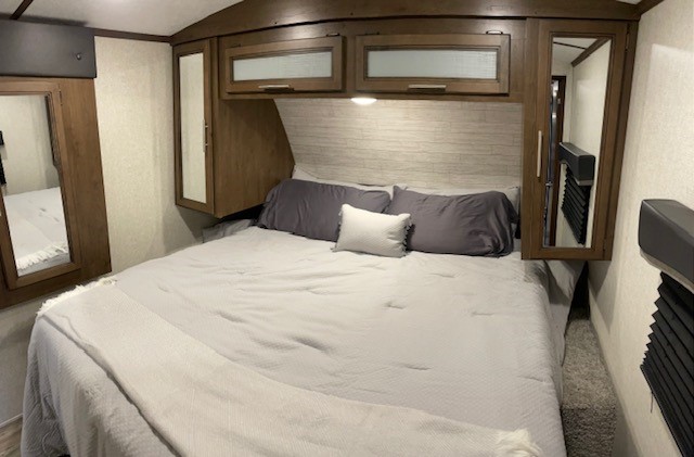 RV rental: Cozy bedroom with queen bed, overhead cabinets, and mirrored wardrobes for comfortable travels.. Keystone Cougar 2020