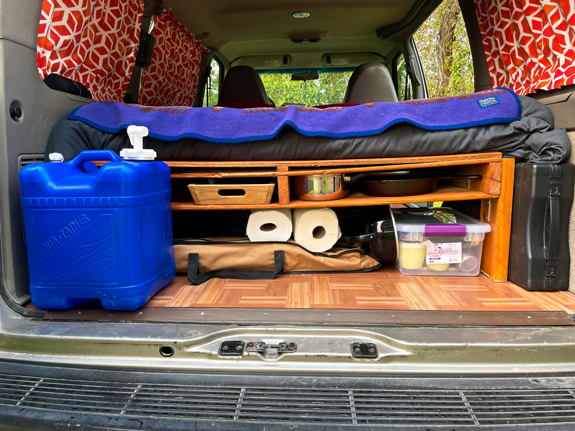 Compact vehicle camping setup for RV rental adventure: bed, organized storage, water, and cooking essentials.. Gmc Other 2004