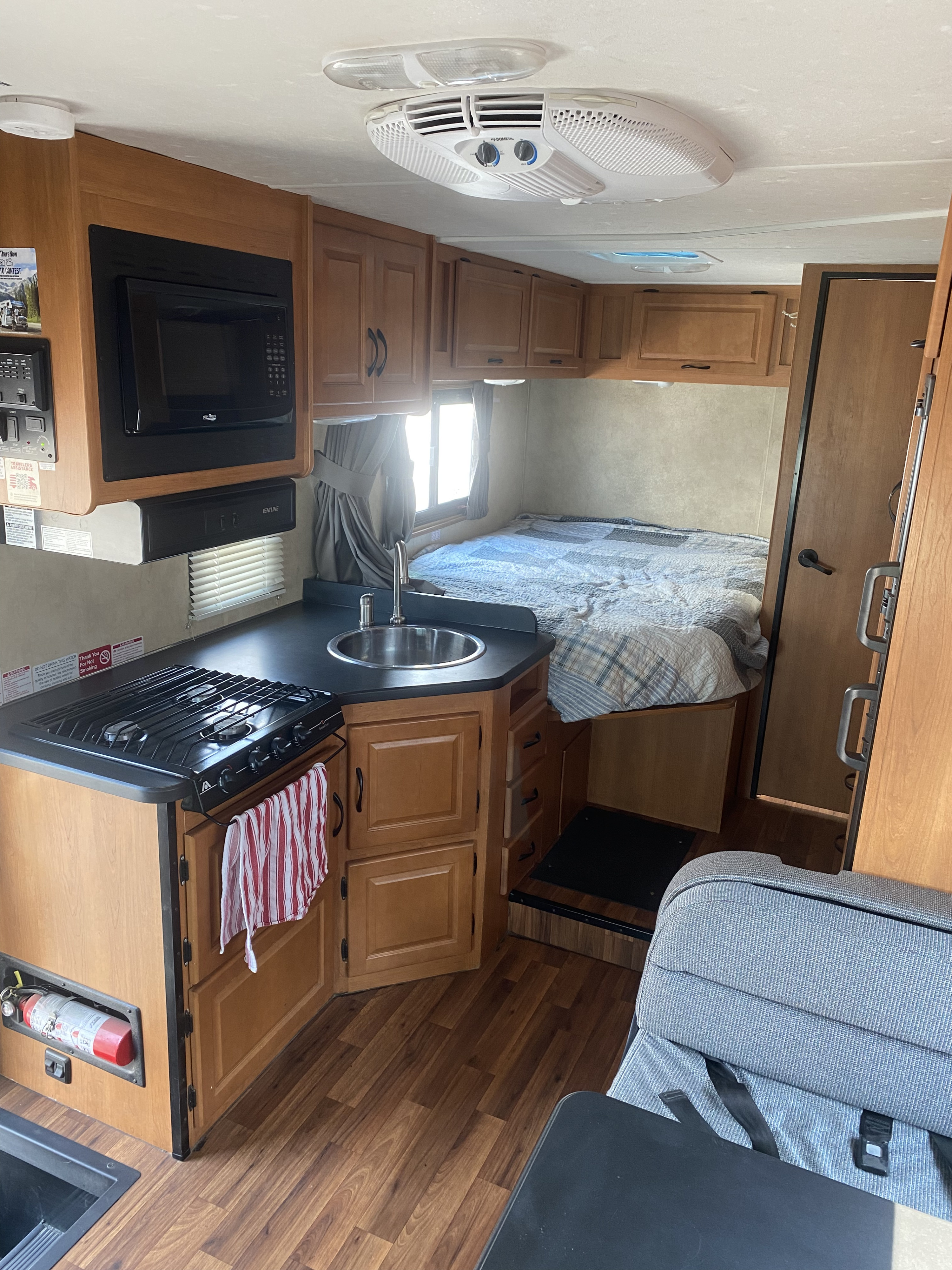 This cozy rv rental interior features a well-equipped kitchen with stove, sink, microwave, and a comfortable bed in back.. Thor Motor Coach Four Winds Majestic 2013