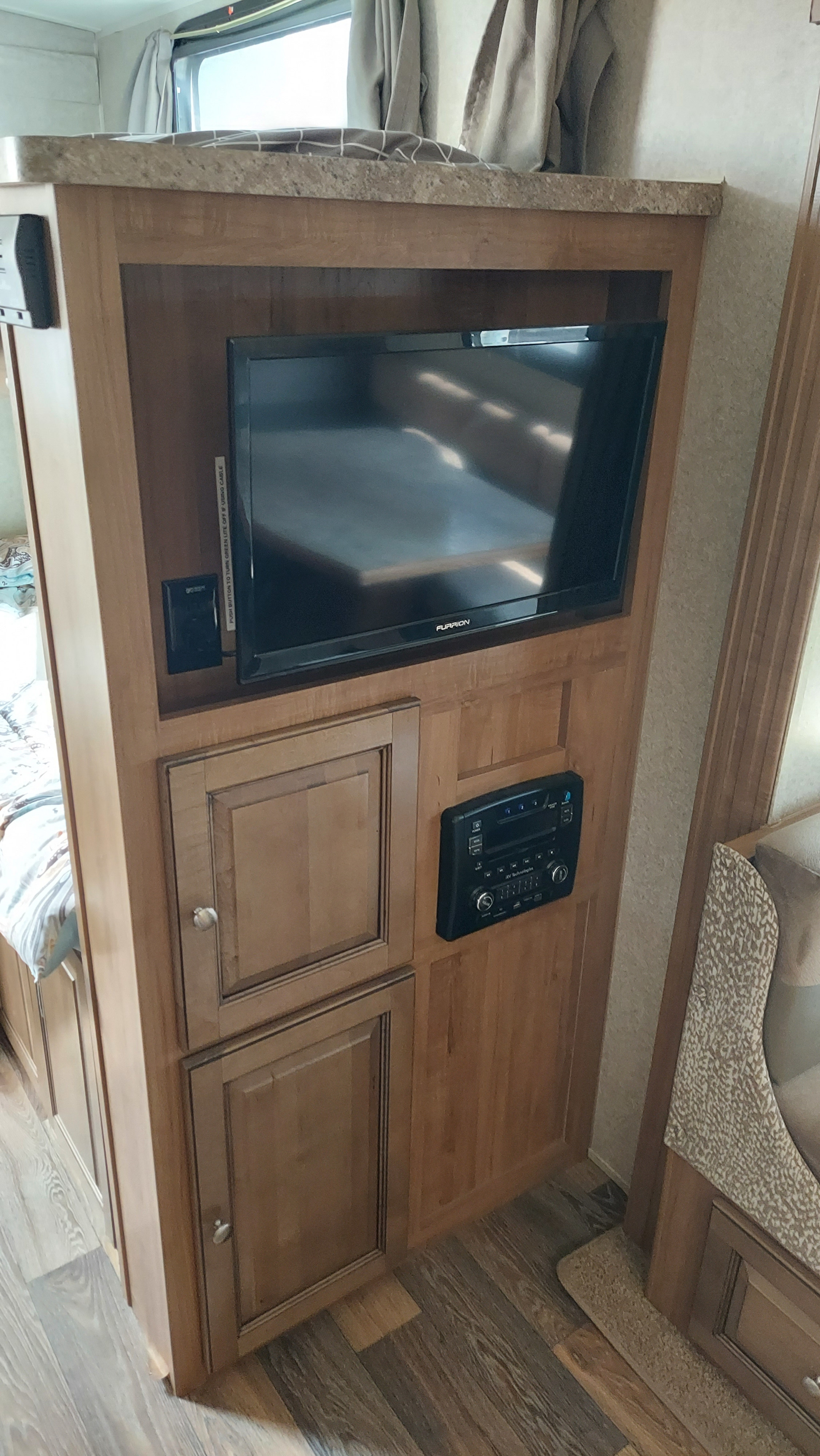 RV rental interior featuring a wooden entertainment center with a Furrion TV, media player, and storage cabinets.. Other Other 2016