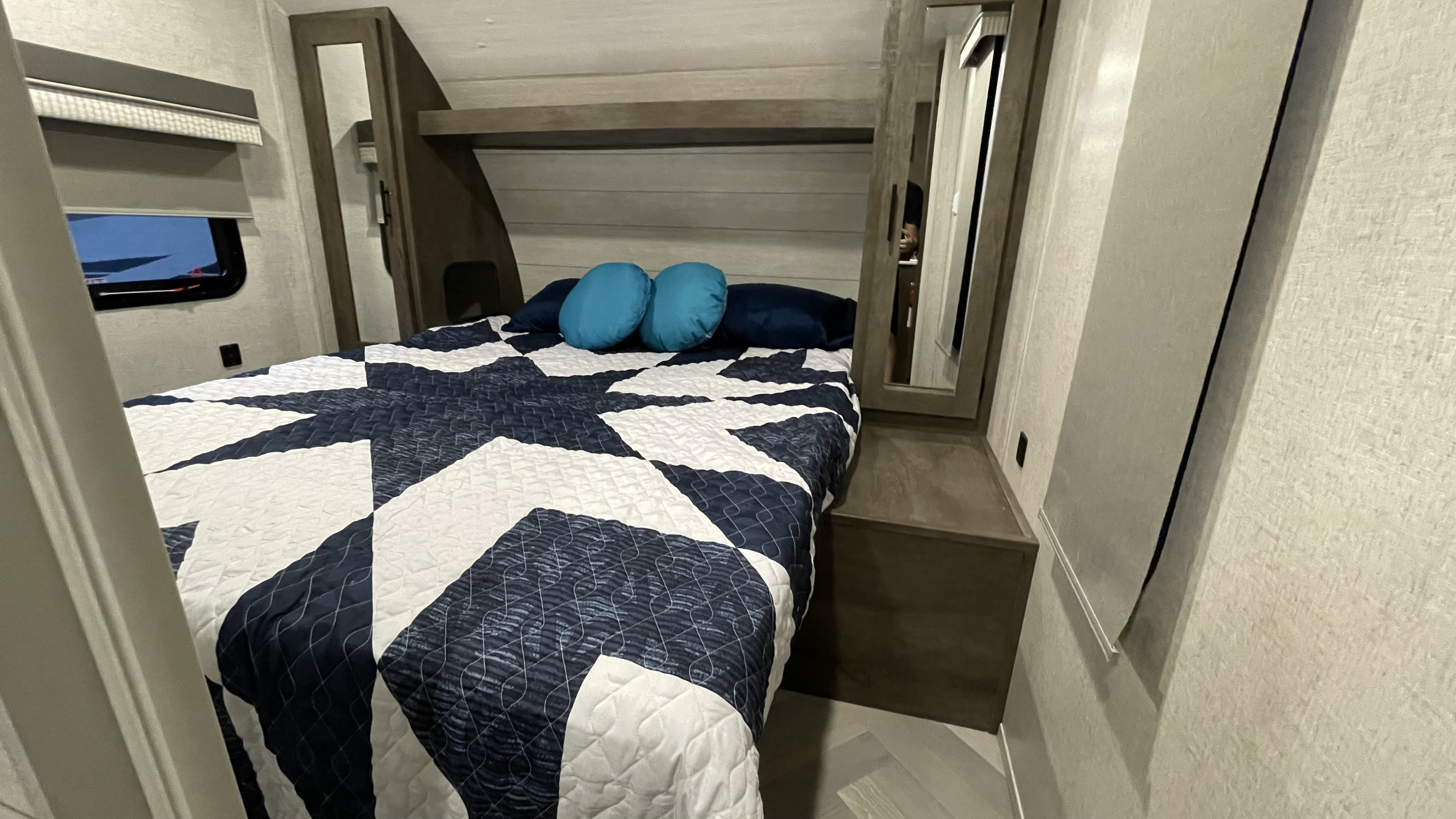 Cozy RV rental bedroom features a bed with a navy/white geometric quilt, blue pillows, and built-in storage.. Forest River Salem Cruise Lite 2021