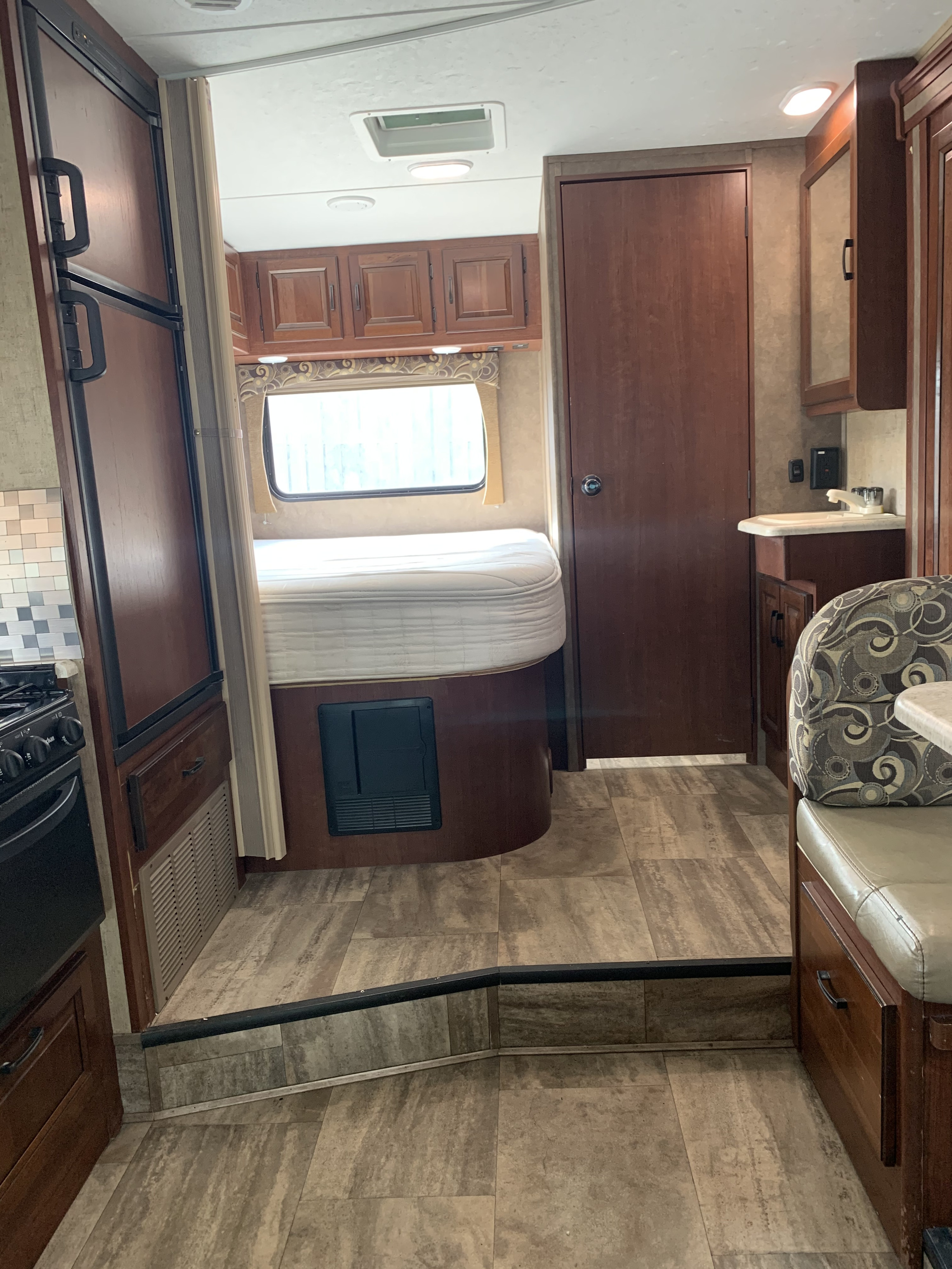 RV rental interior showcasing a compact and functional living space with a bedroom, kitchen, and bathroom sink area.. Forest River Sunseeker 2016