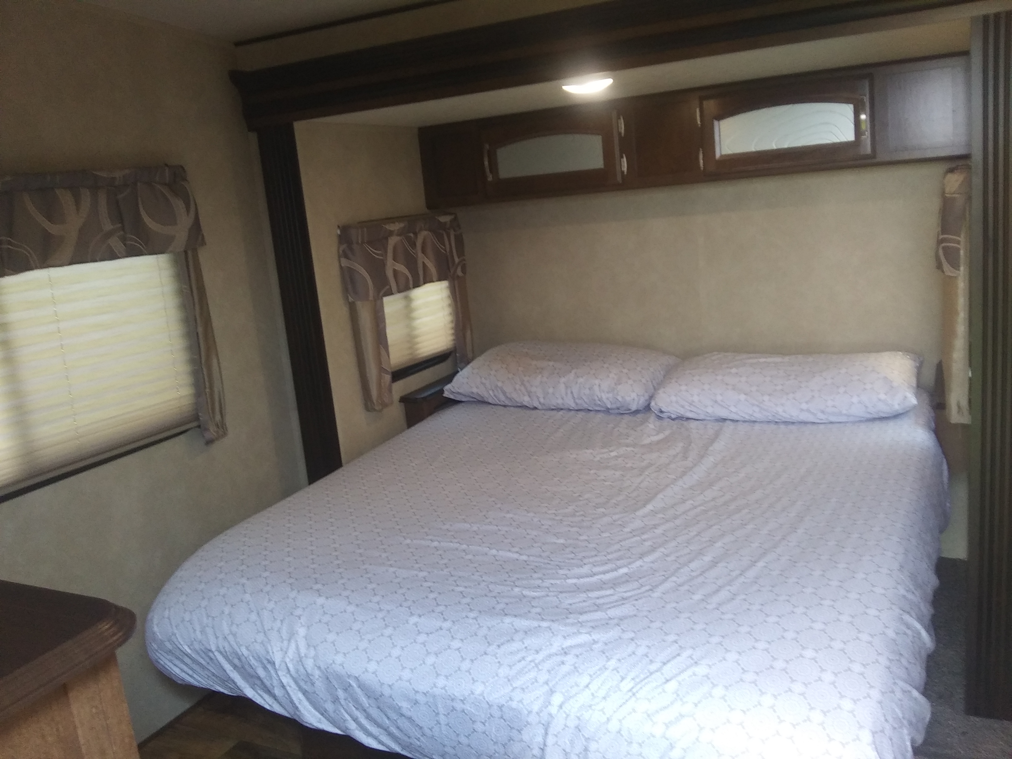 Cozy RV rental bedroom featuring a spacious bed, bright pillows, and convenient overhead storage.. Forest River Salem Hemisphere 2017