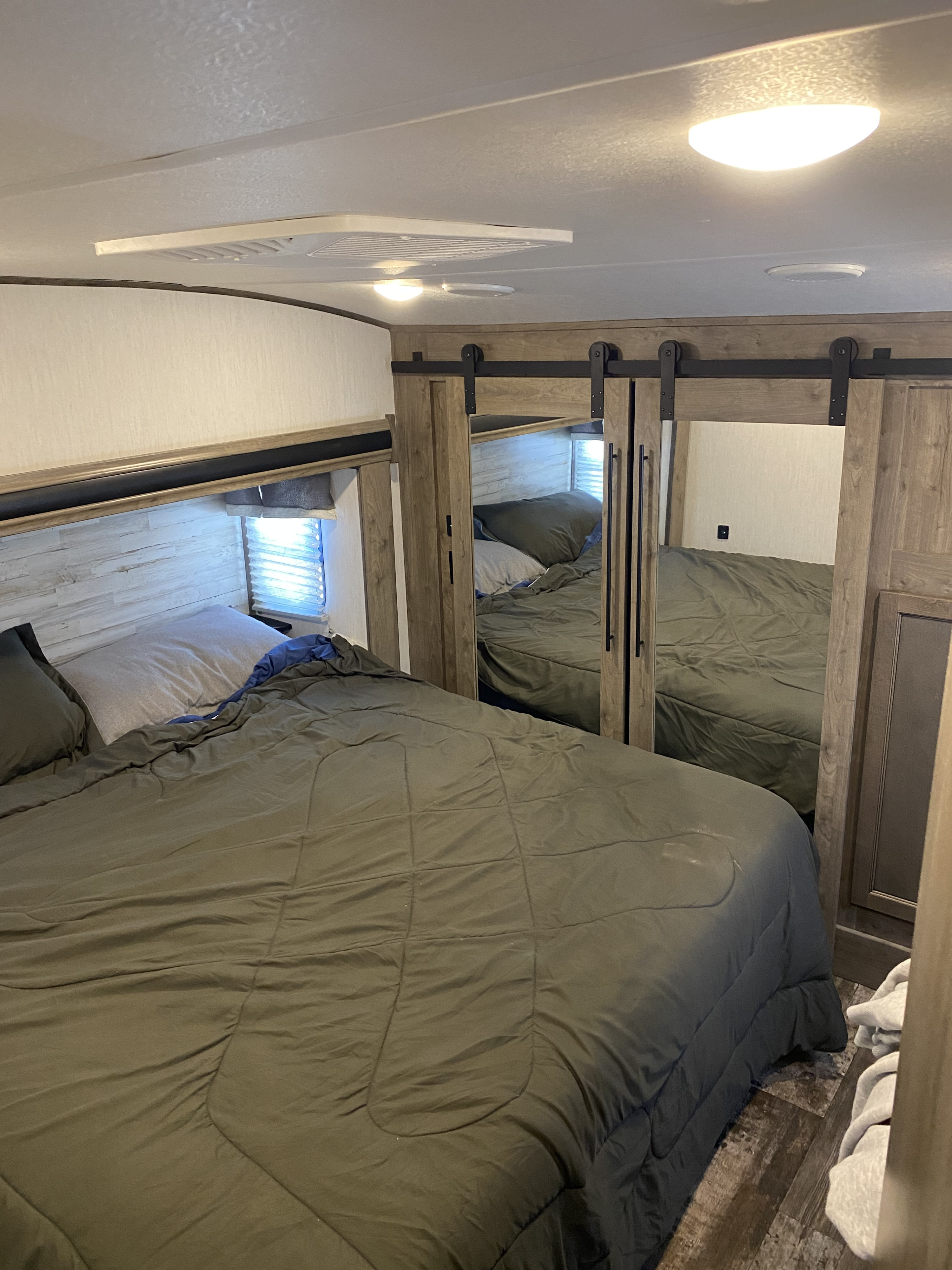 Experience comfort in this RV rental bedroom with a large bed, mirrored closet, and wood-paneled walls.. Forest River Other 2021