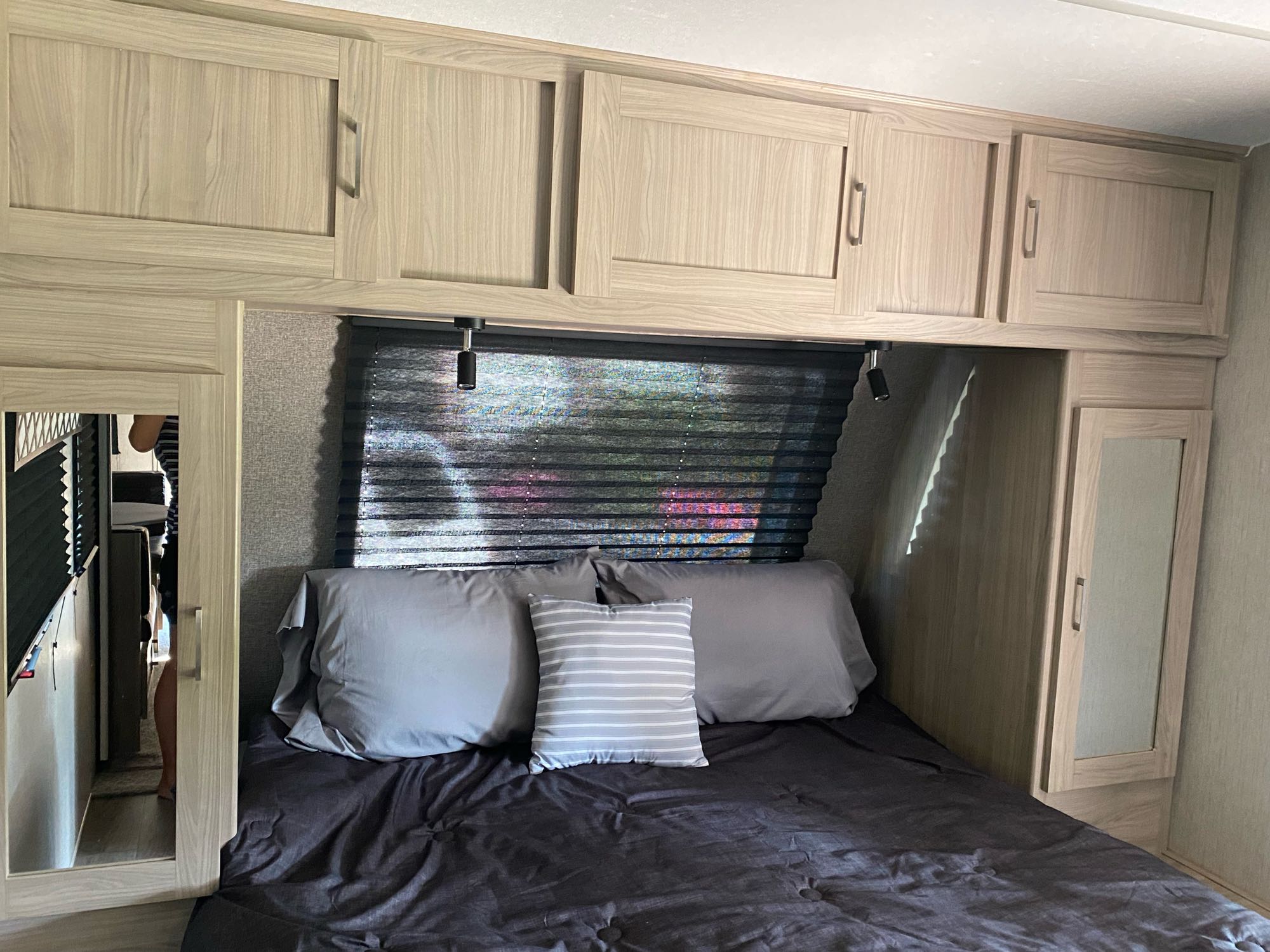 Cozy RV rental bedroom with a comfortable bed, ample overhead storage, and mirrored cabinets, maximizing space for travelers.. Coachmen Freedom Express 2020