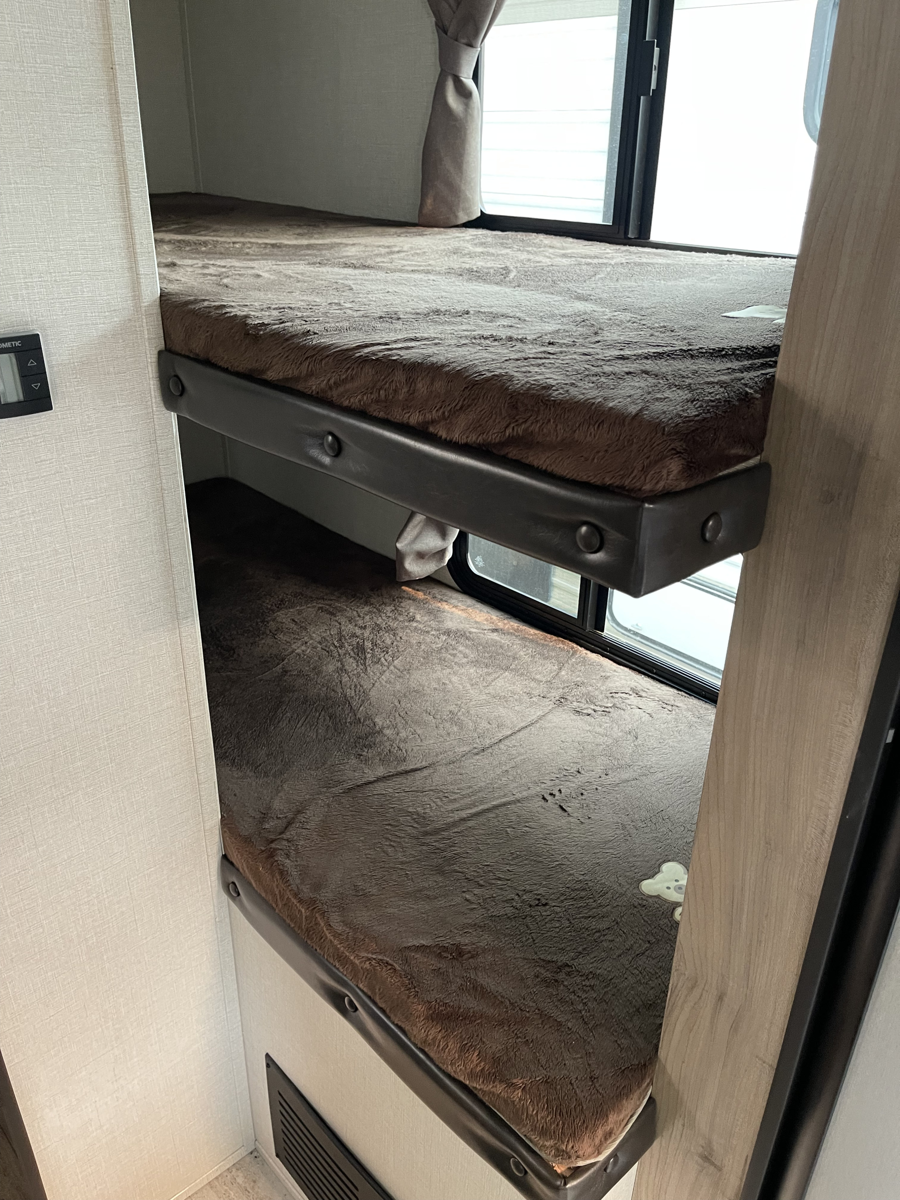 Two comfy bunk beds with brown faux fur bedding inside an RV rental, perfect for family travel.. Solaire 211BH 2019
