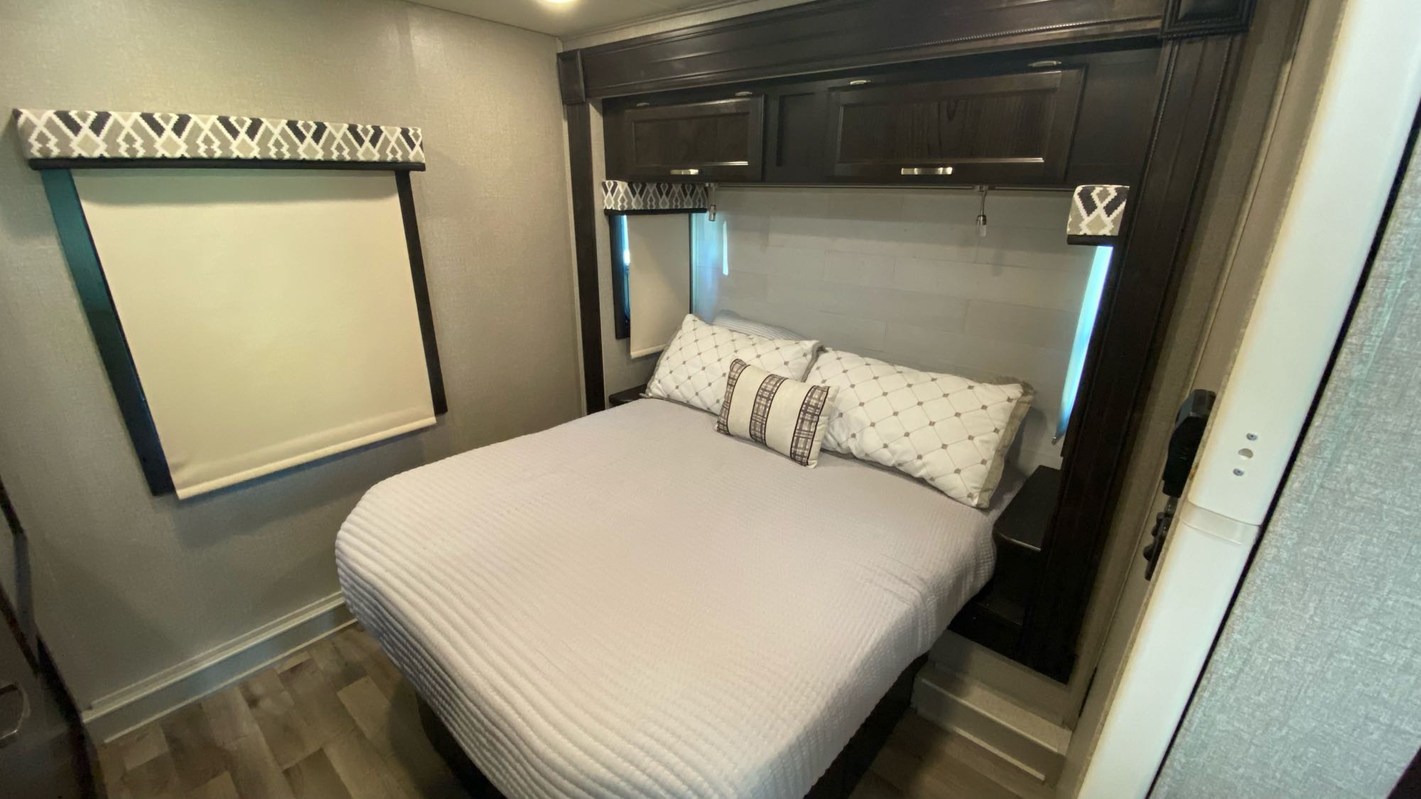 Compact RV rental bedroom featuring a cozy bed, overhead storage, and window with a shade for your next adventure.. Jayco Greyhawk 2020