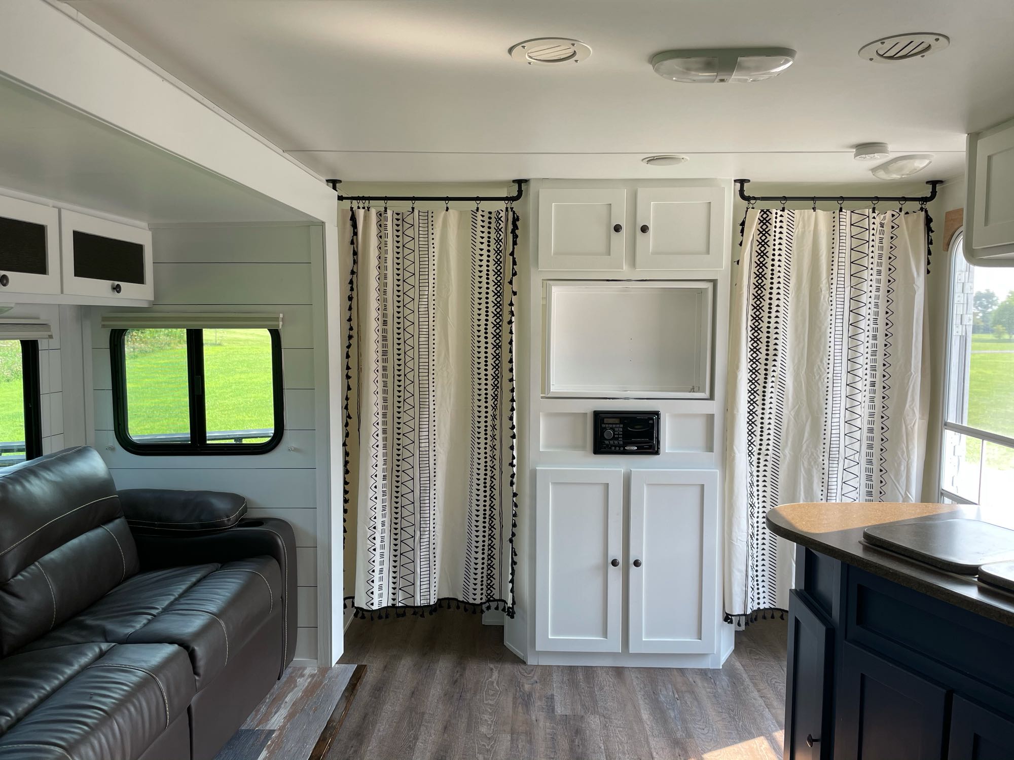 Inside a modern **rv rental**: bright interior with white cabinets, wood floors, comfy sofa, & stylish black/white curtains.. Cruiser Rv Corp Shadow Cruiser 2011