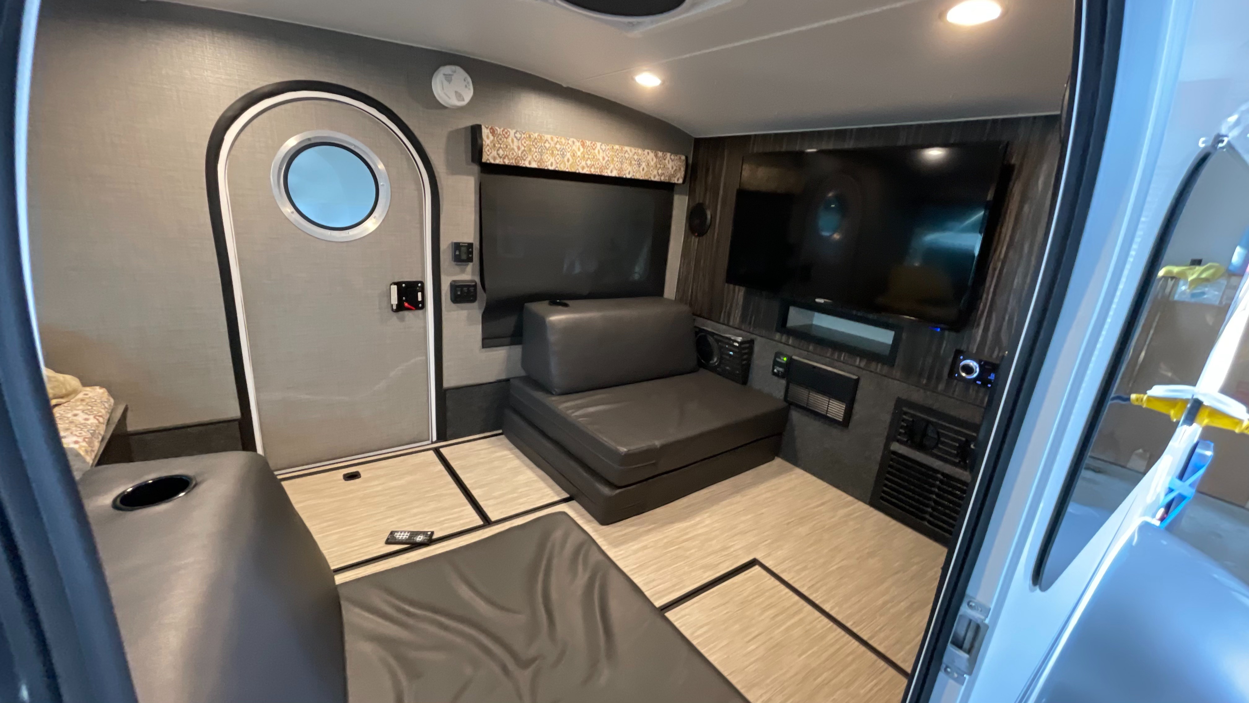 Explore this cozy RV rental interior! Features include convertible seating, a large TV, and a distinctive porthole door.. Other Other 2018