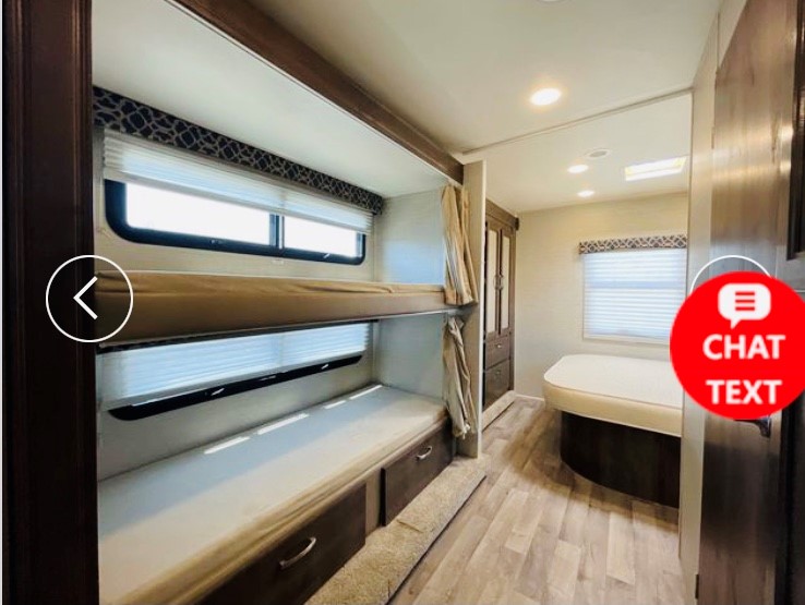 View inside an RV rental showing comfortable bunk beds, windows, and a curved sleeping area, ideal for family travel.. Jayco Redhawk 2018