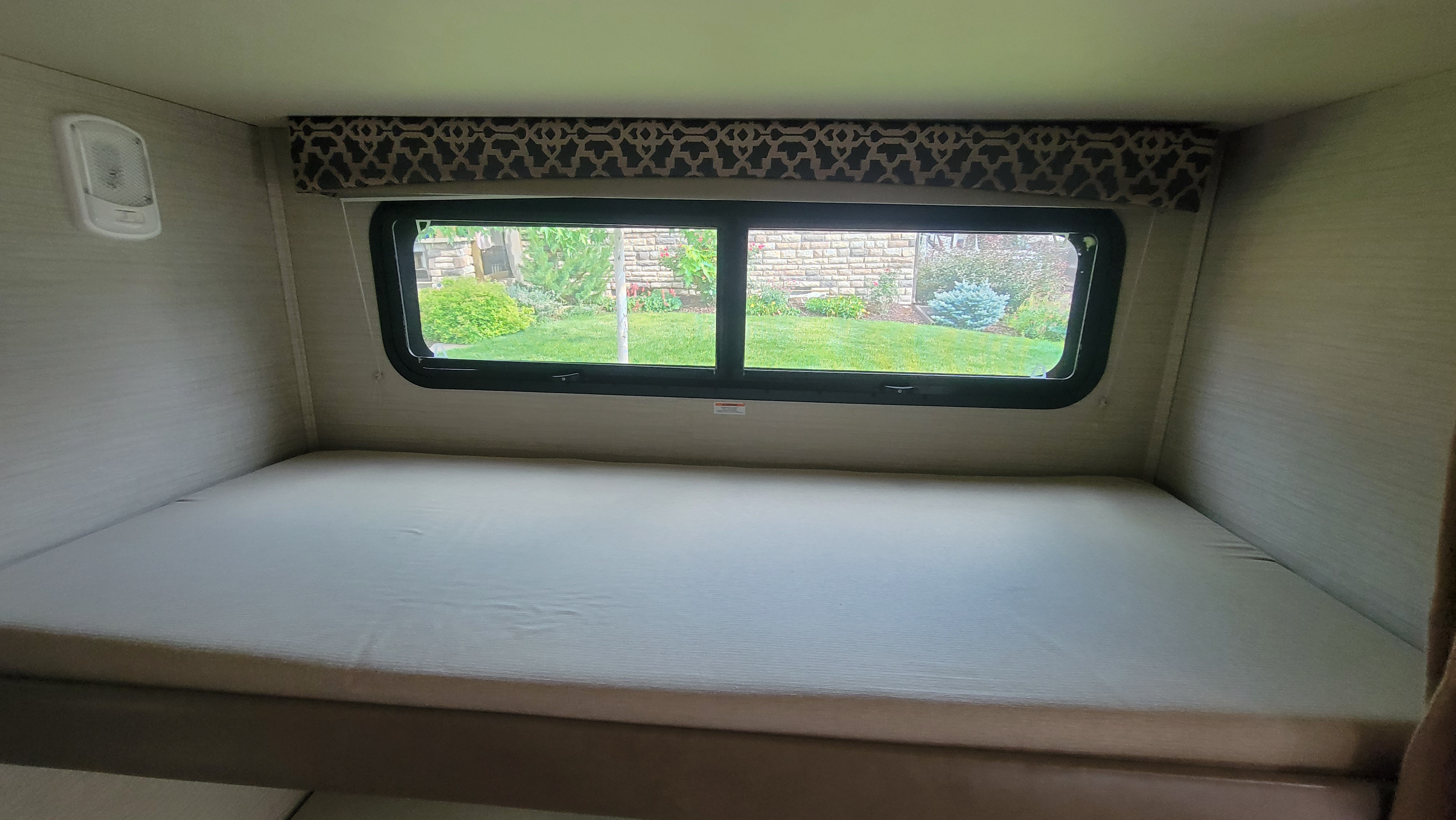 RV rental: Interior of a comfortable RV bunk bed area with a large window looking out to a green garden. Overhead light.. Jayco Redhawk 2018