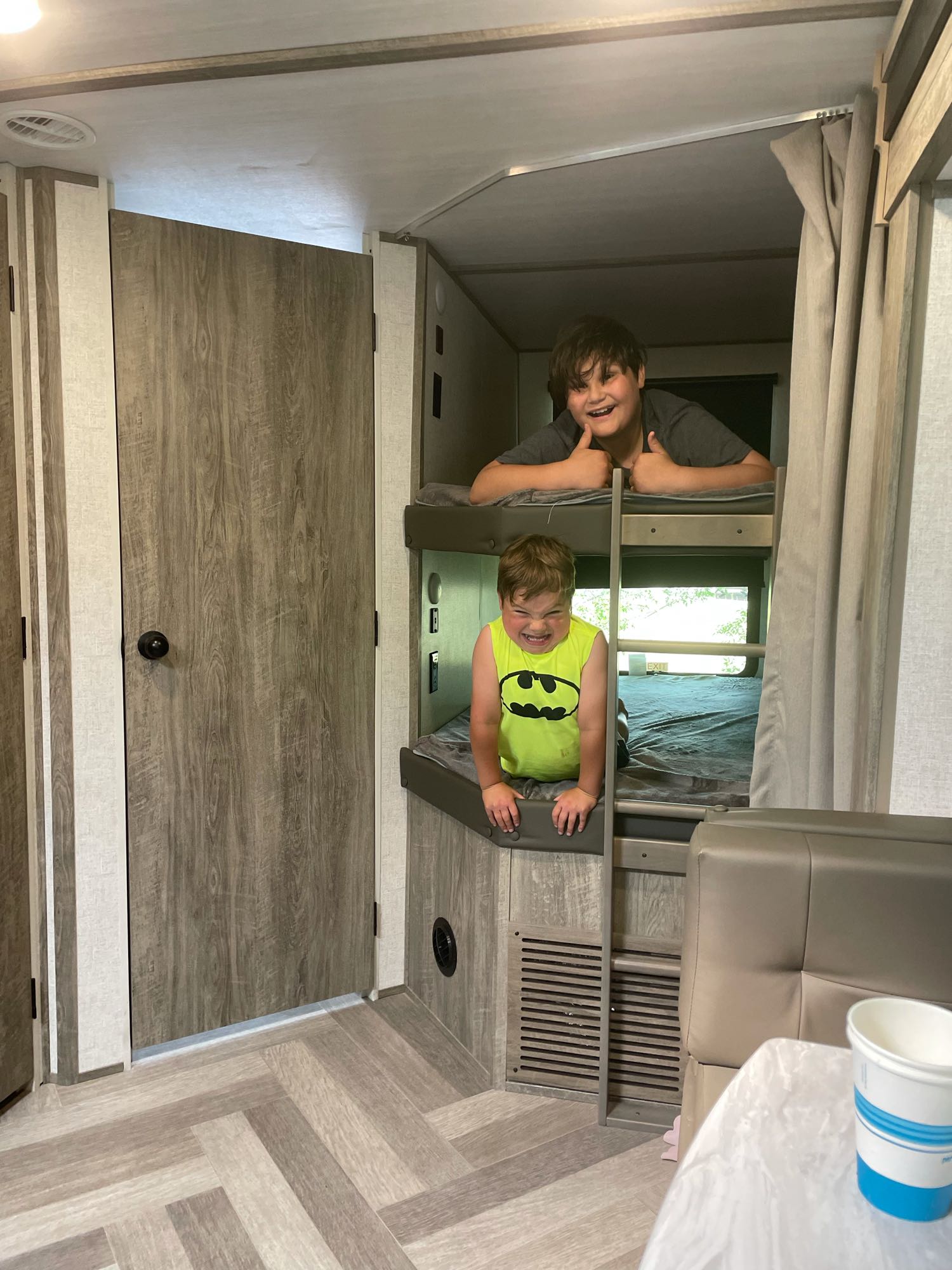Two boys playfully pose in the bunk beds of an RV rental, showcasing the cozy travel trailer interior.. Forest River Salem Hemisphere 2021