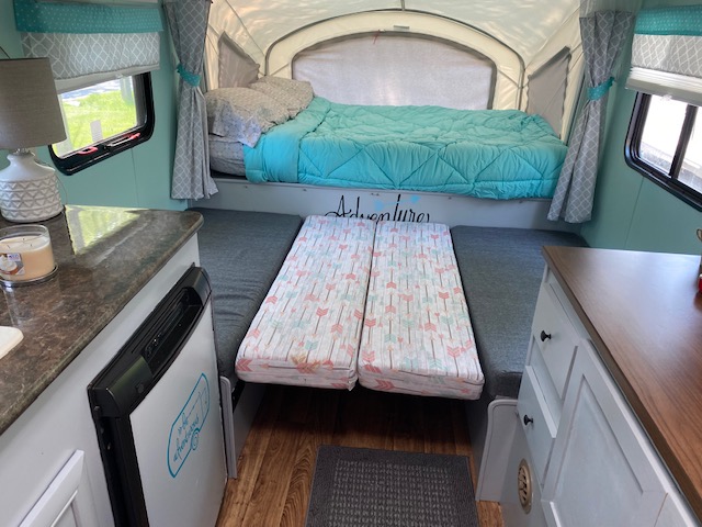 RV rental: Cozy pop-up camper interior features a teal bed, kitchen counter, and convertible seating, decorated for adventure.. Skyline Bobcat 2012
