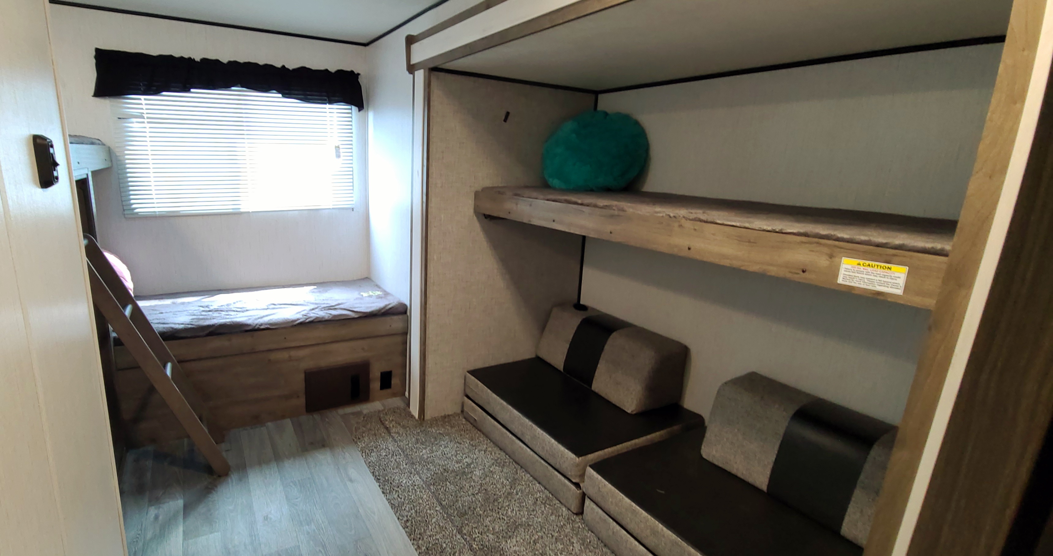 This RV rental features a cozy bunk room with twin beds, convertible sofas, and a large window, offering comfortable sleeping and lounging.. Heartland Pioneer 2021