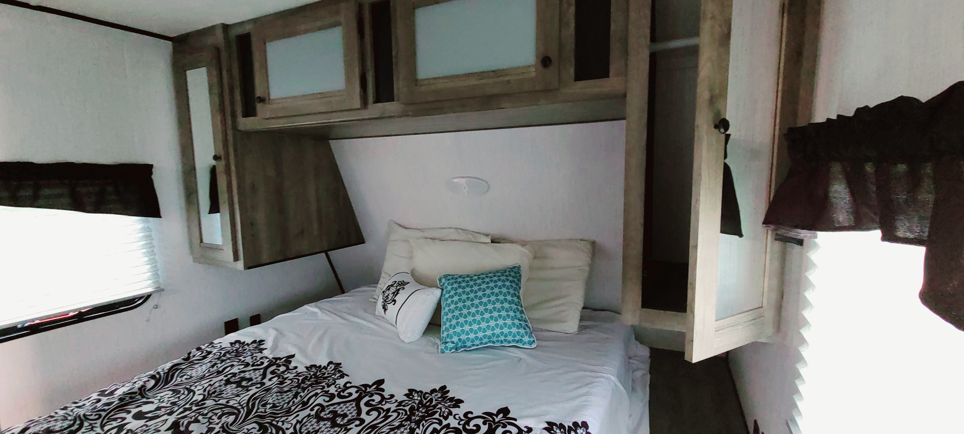 RV rental bedroom: cozy space with bed, pillows, overhead cabinets, and window. Perfect for your next adventure.. Heartland Pioneer 2021