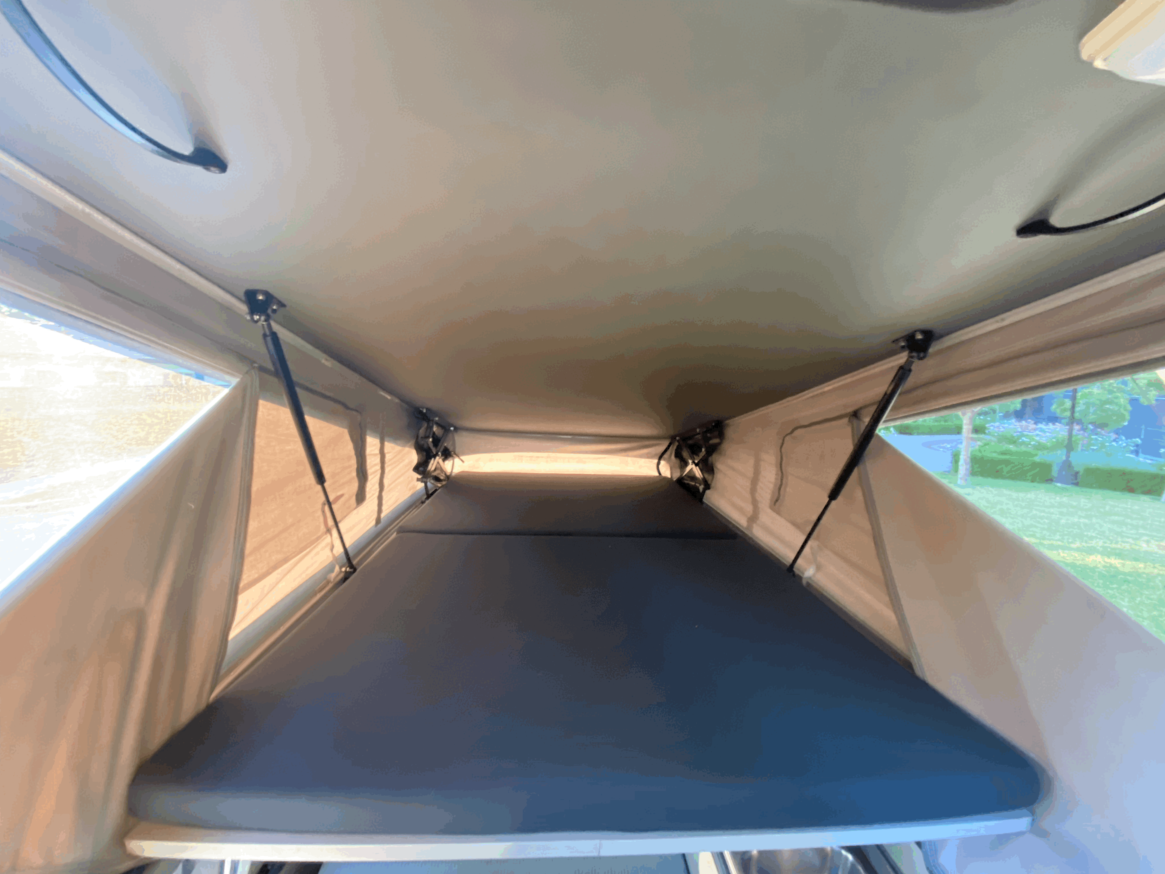 Spacious interior of an RV rental rooftop tent, showcasing a comfortable mattress and lift mechanism, ready for sleep.. Volkswagen T4 Multivan Westfalia 1995