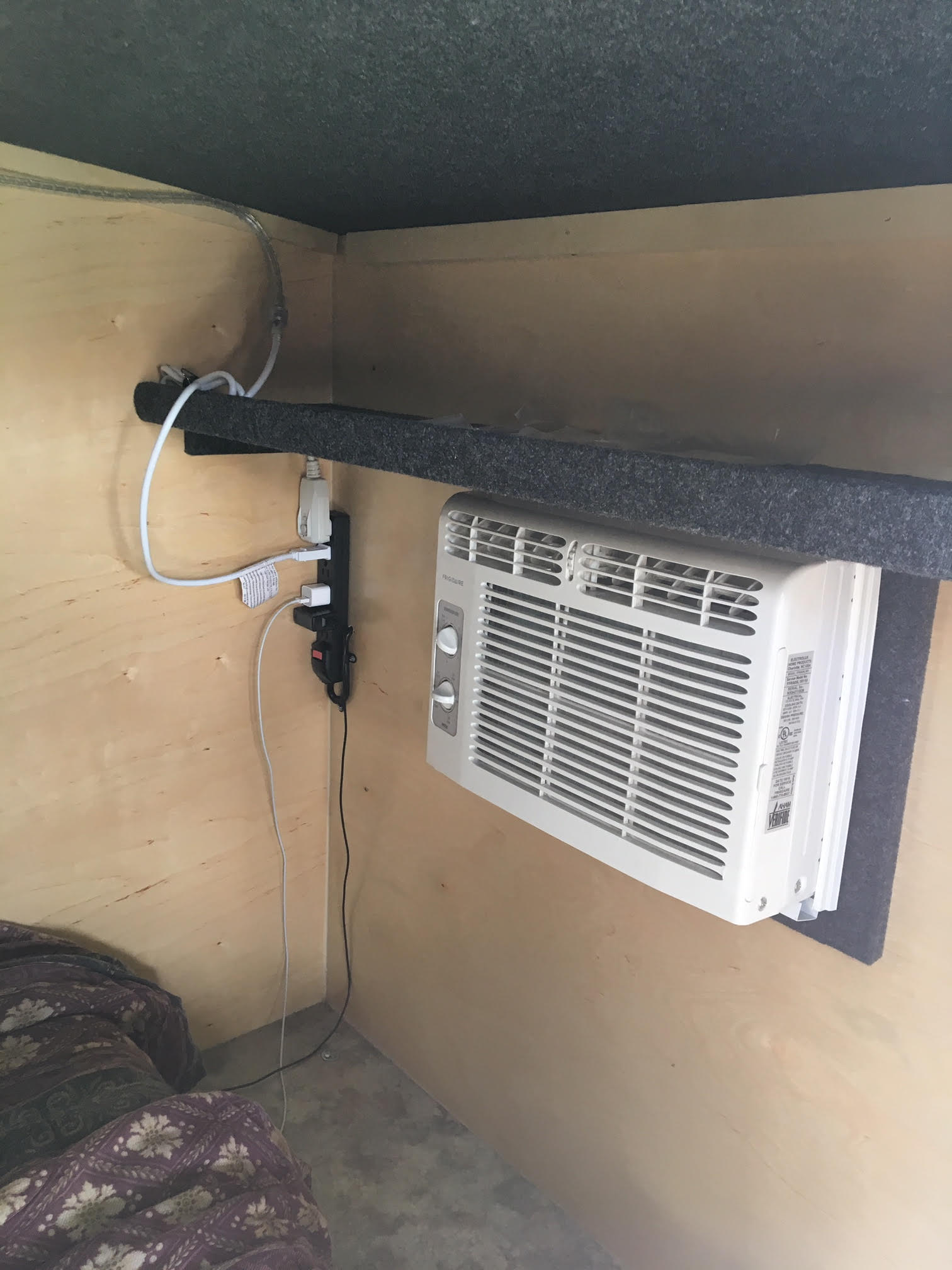 RV rental setup: A compact AC unit and power strip installed on wooden walls near a bed.. Runaway Campers Navigator 2017