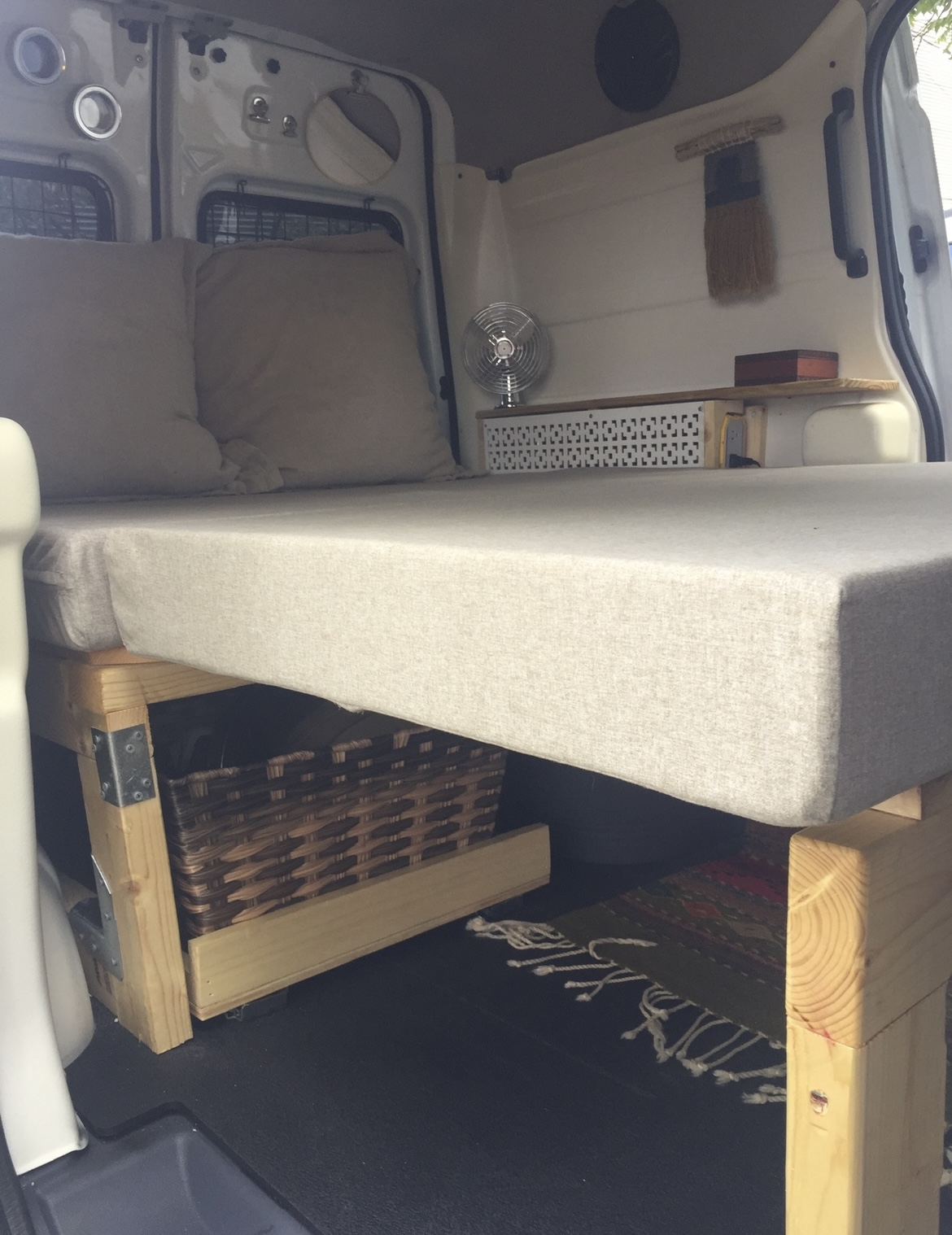 A comfortable RV rental interior with a bed, pillows, under-bed storage (basket, rug), and. Ford Transit custom 2012