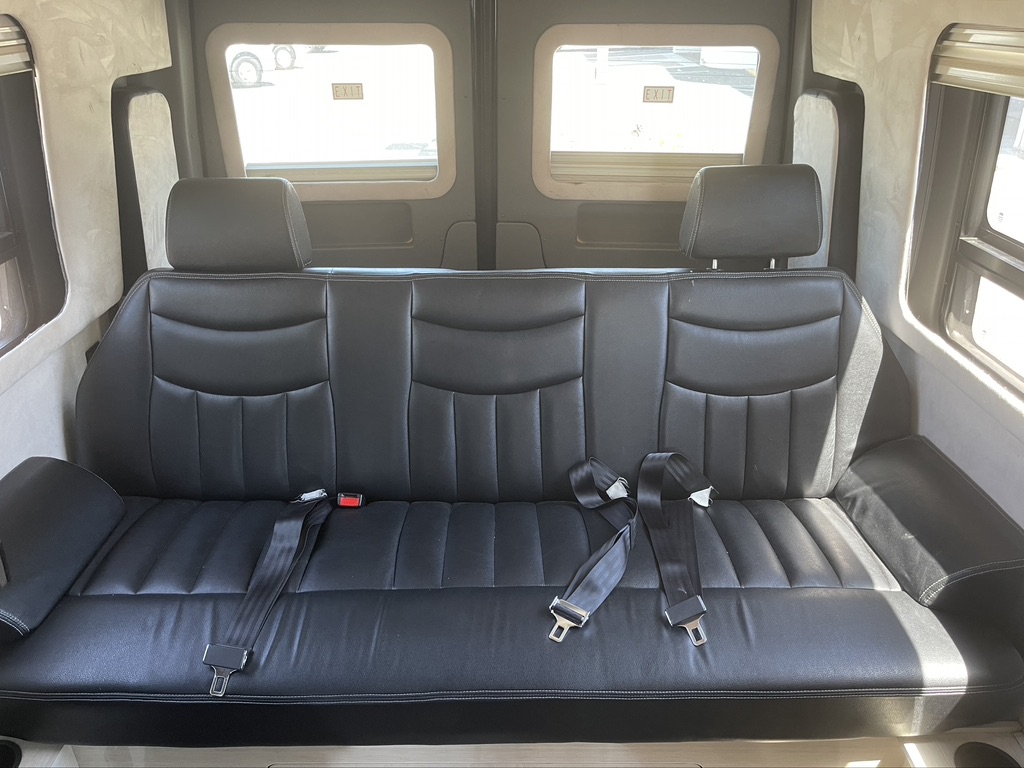 Spacious black leather bench seat inside an RV rental, offering comfortable passenger seating with multiple seatbelts.. Airstream Interstate 2013