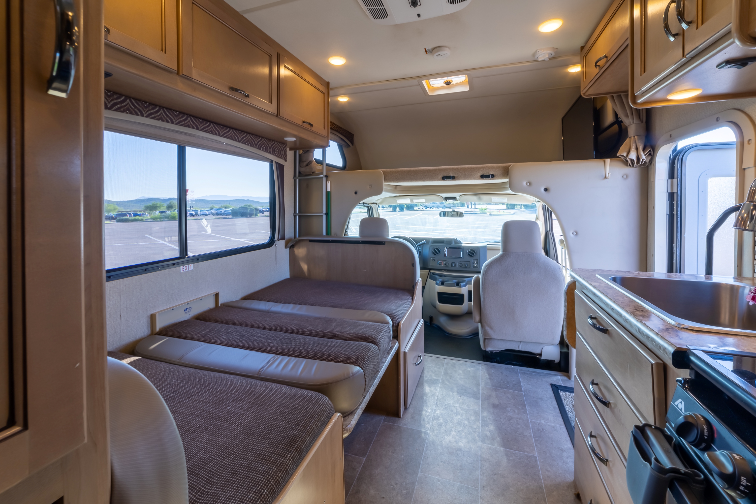Interior of an RV rental showing a spacious cabin with beds, kitchen, and cockpit. Ready for your travel adventures.. Thor Motor Coach Chateau 2018