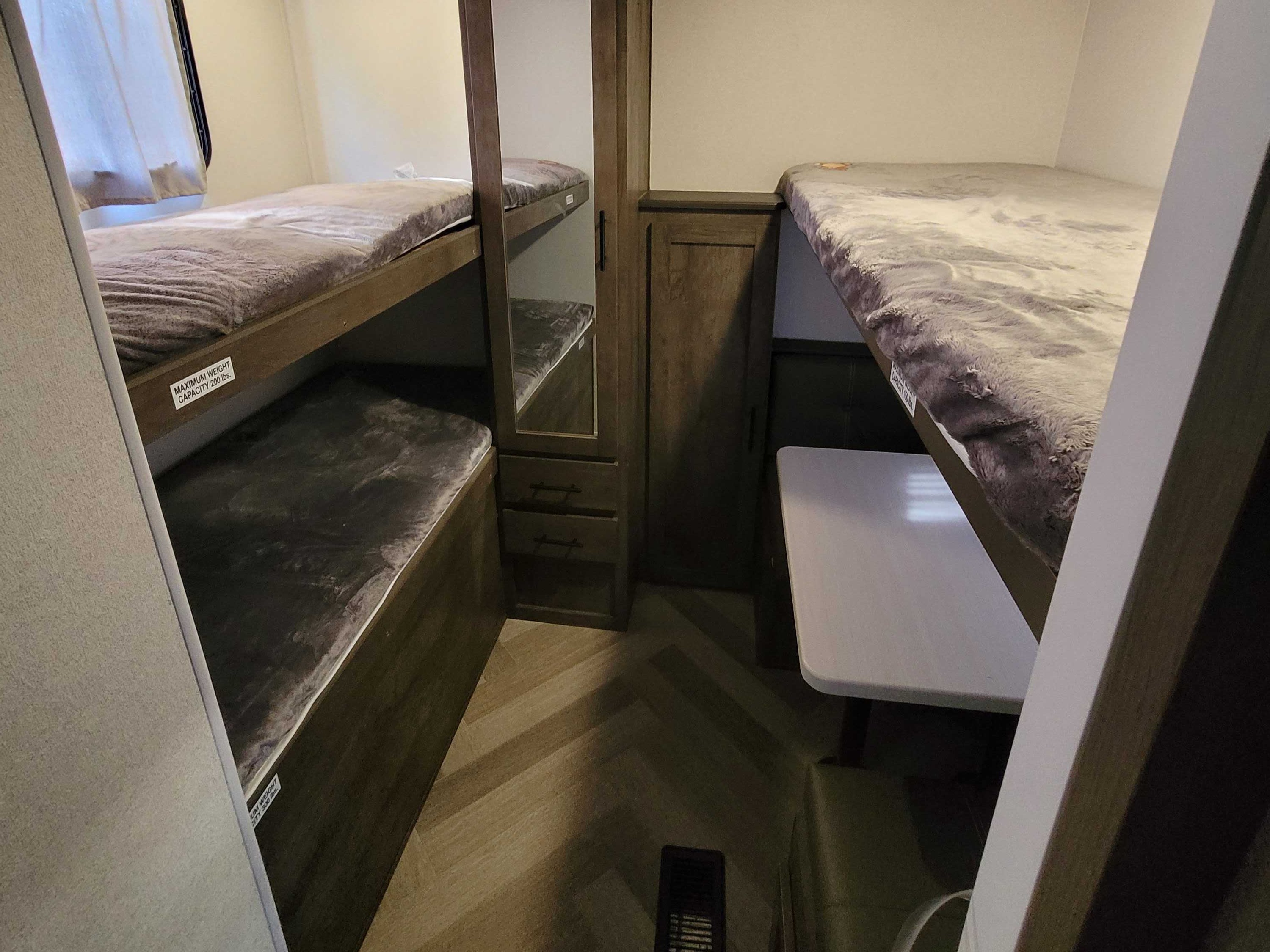 This RV rental offers cozy bunk beds, a central cabinet with mirror, and a small dining table for compact living.. Forest River Salem 2021