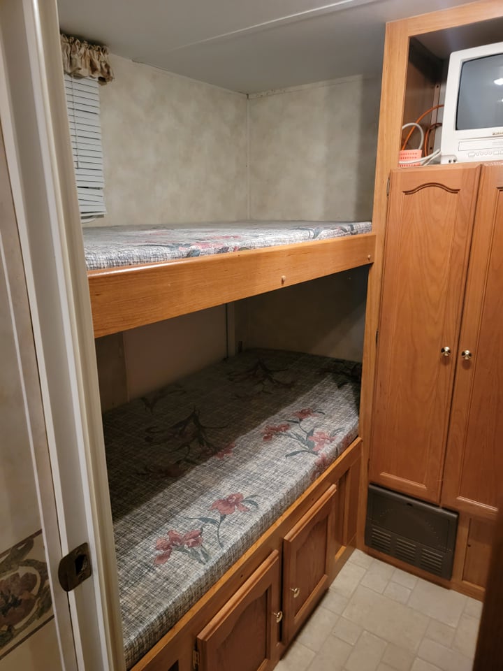 This RV rental showcases two compact bunk beds with storage below, plus a small TV. Perfect for family travel.. Palomino Puma 2005