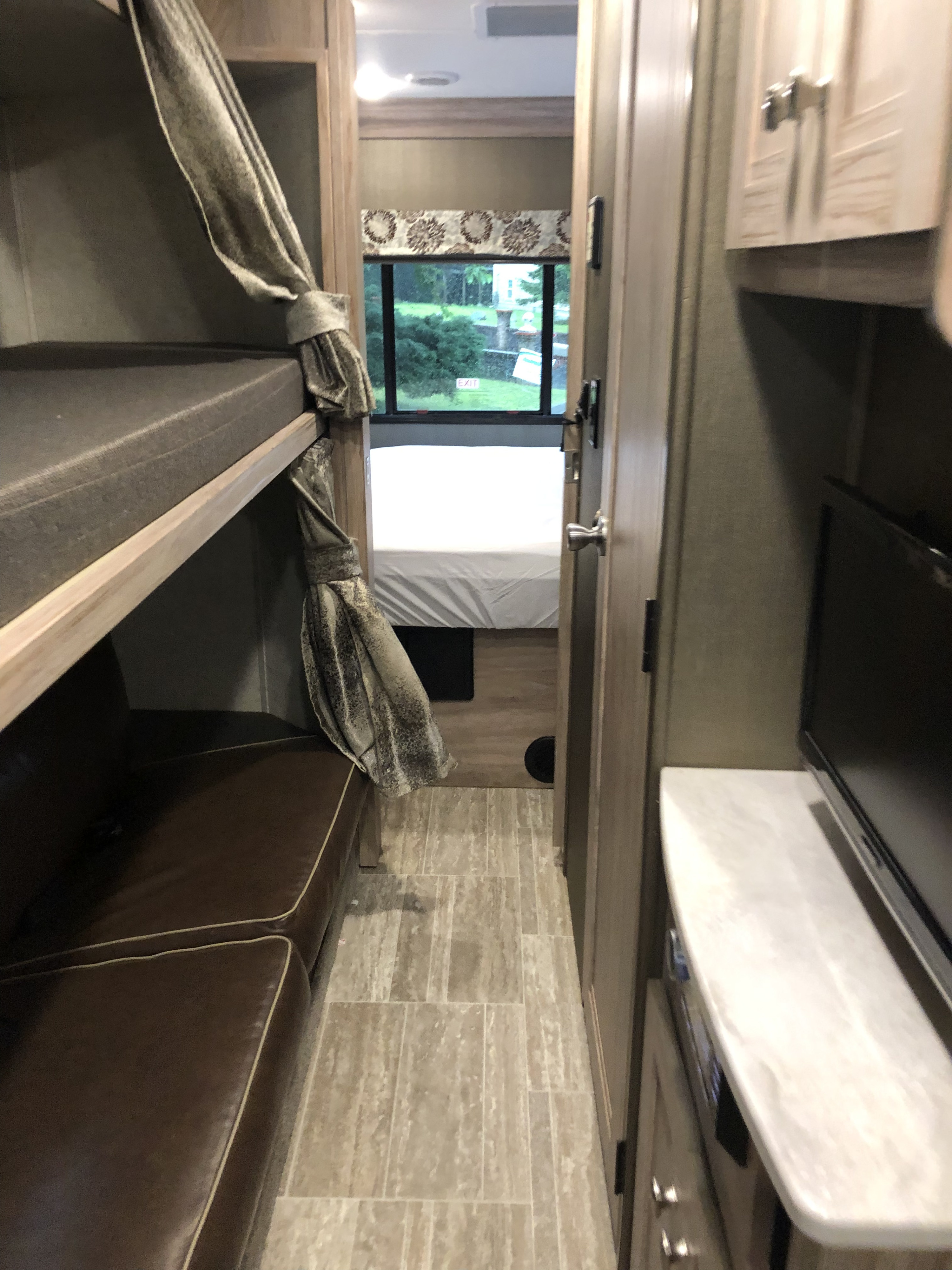 Spacious RV rental interior featuring bunk beds, a hallway to a rear bedroom, and a TV setup. Perfect for family trips.. Forest River Forester 2019