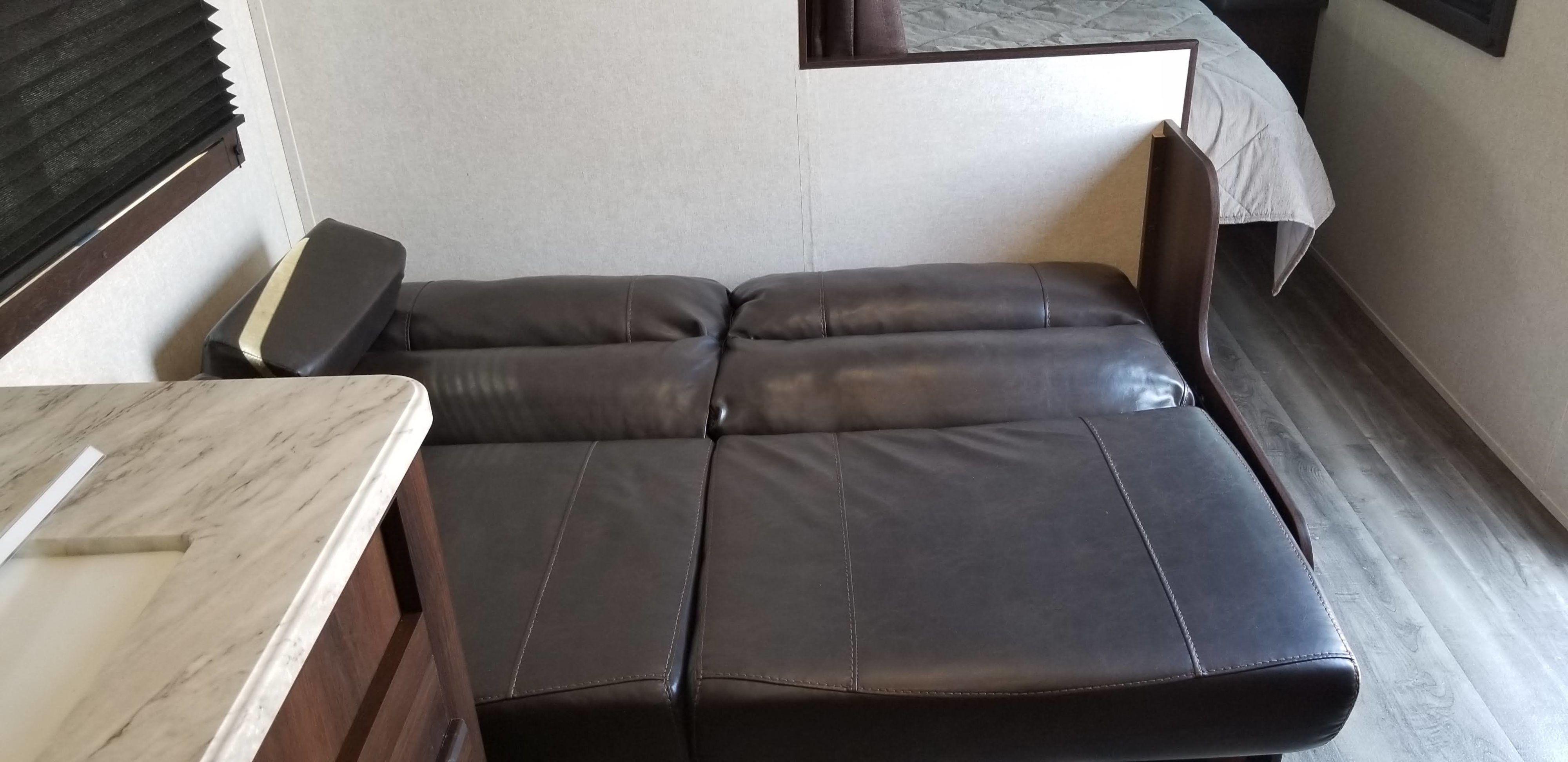 RV rental interior with a dark leather convertible sofa, a countertop, and a bed visible in the rear.. Jayco Jay Flight 232 RBW with Rocky Mountain and Baja upgrades 2020