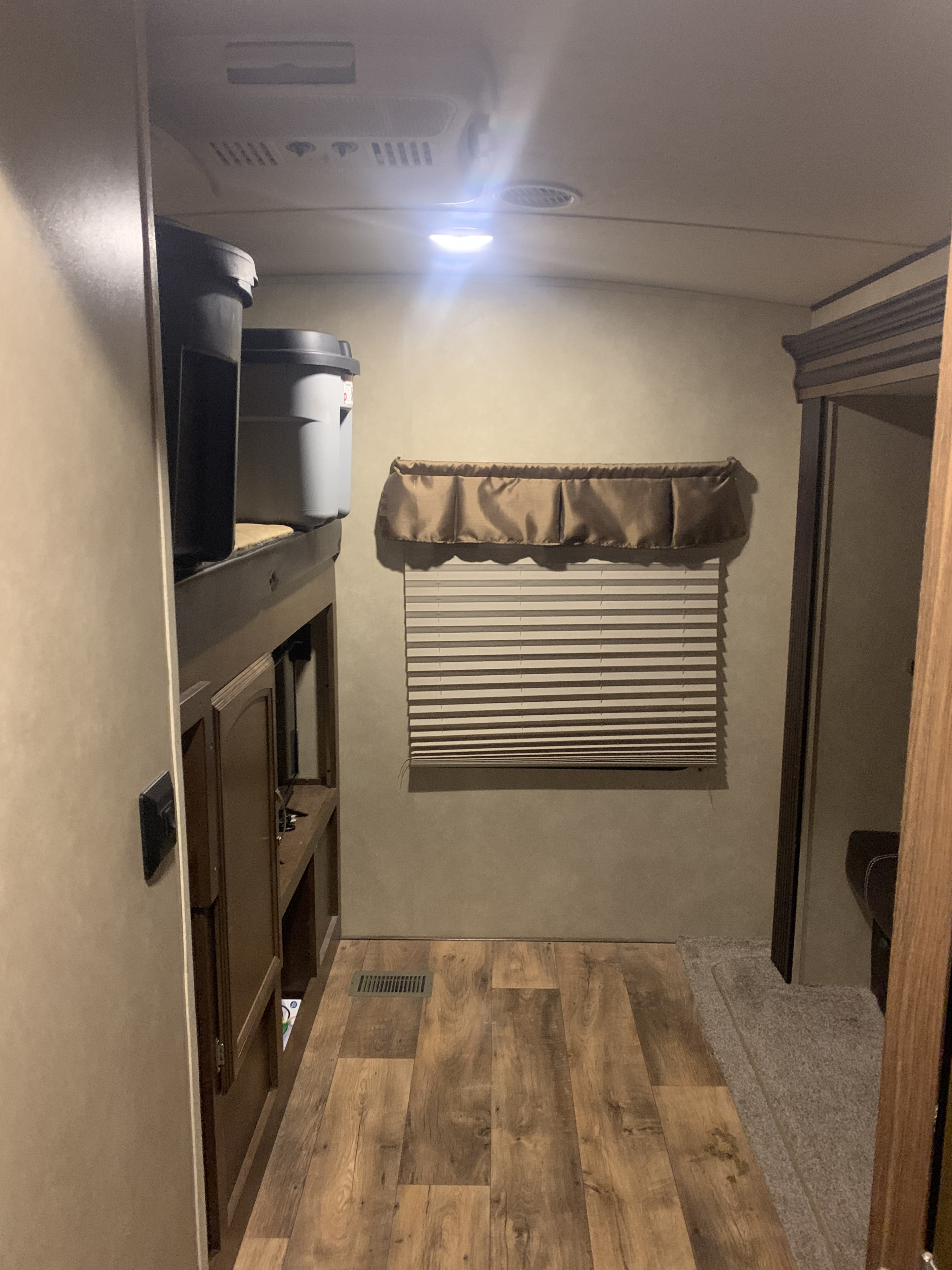 RV rental bunk area featuring storage, laminate floor, and window blinds, designed for compact living.. Forest River heritage glen q312bud 2017
