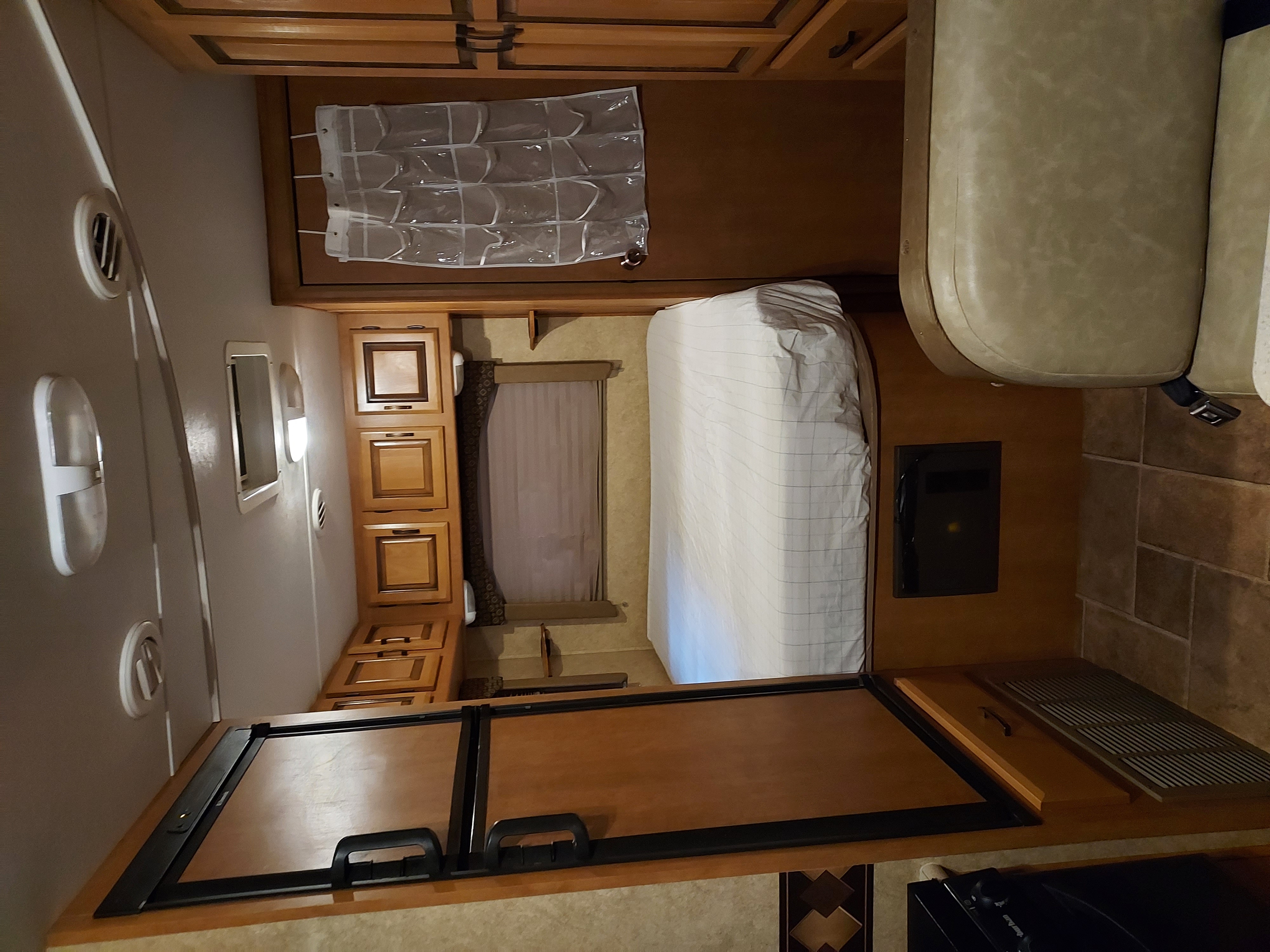 RV rental interior showcasing a bed, seating, wooden cabinets, and built-in appliances for your journey.. Forest River Sunseeker 2011