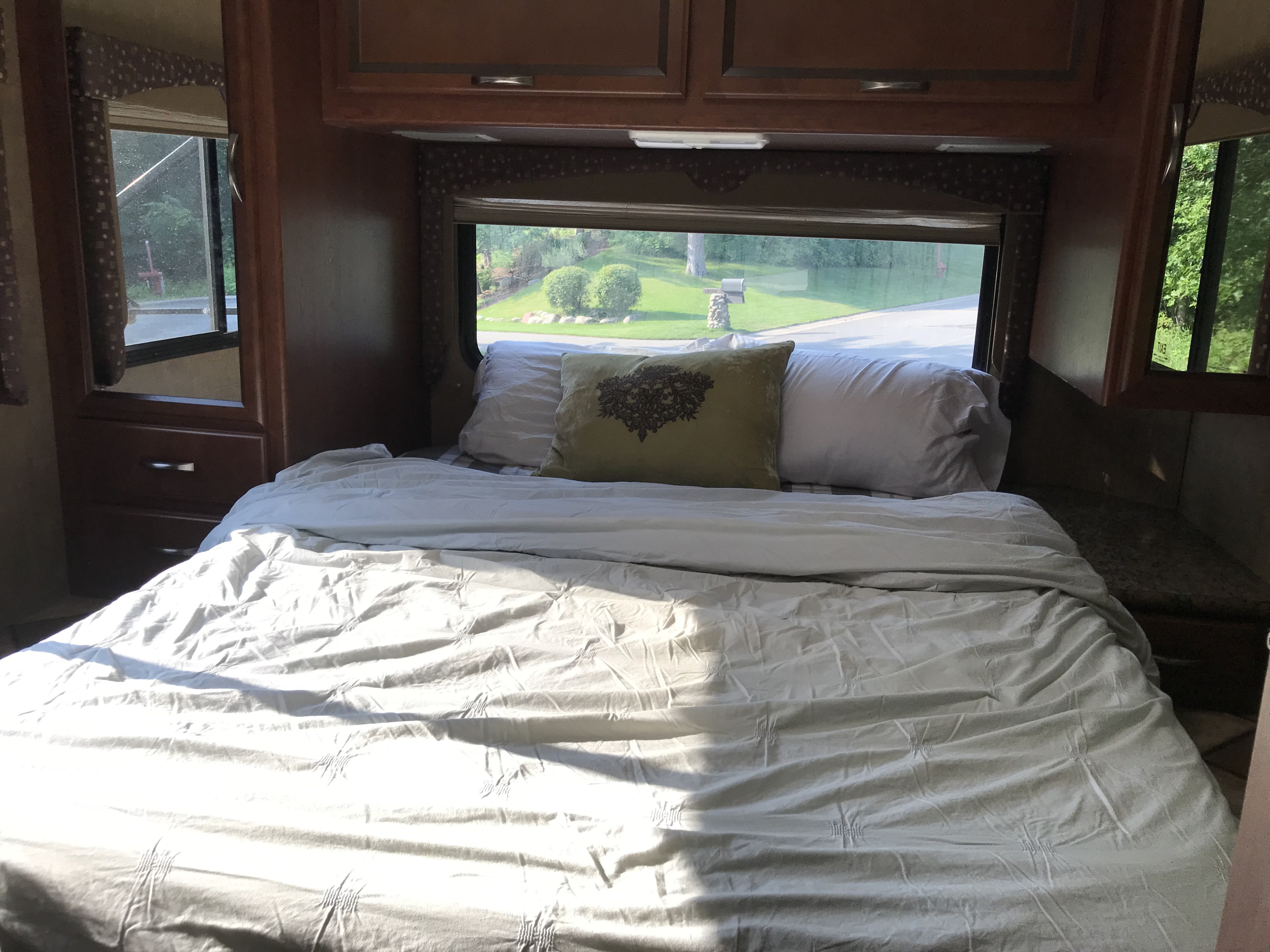 An inviting RV rental bedroom with a comfortable bed, soft pillows, and a window view of the outdoors. Perfect for travel.. Thor Motor Coach Freedom Elite 2015