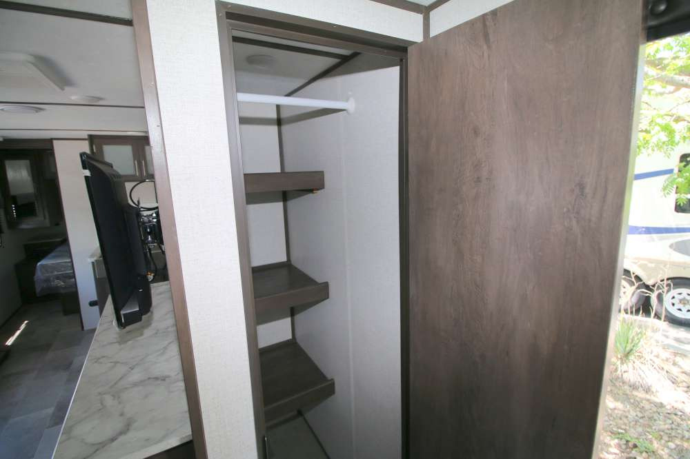 Inside this RV rental: a versatile storage area with a wardrobe rod and shelves, plus a mounted TV for entertainment.. Coleman Other 2021