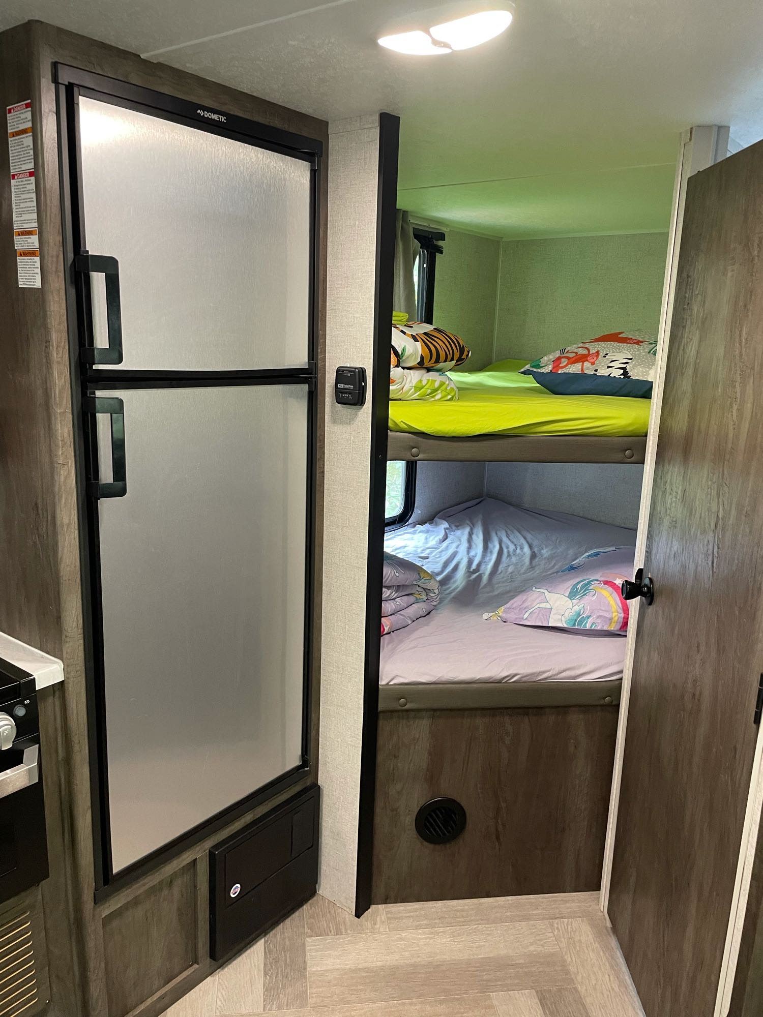 An rv rental interior with a tall refrigerator on the left and cozy stacked bunk beds on the right, great for family travel.. Forest River Wildwood X-Lite 2020