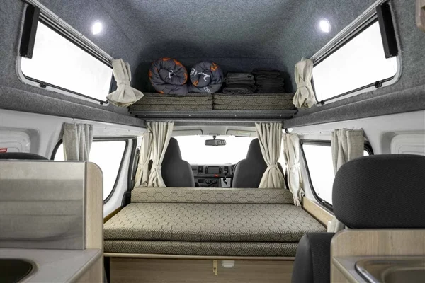 Spacious campervan RV rental interior with bed, overhead storage, and kitchen area, offering comfort for travel.. Toyota HiAce 2014