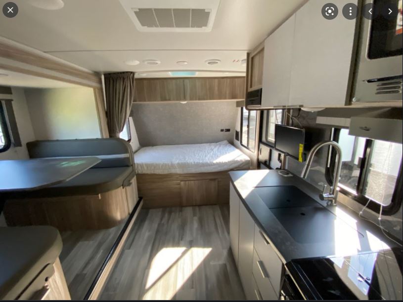 Modern rv rental interior with compact kitchen, bed, and dinette. Bright, versatile living space.. Winnebago Minnie Winnie 2021