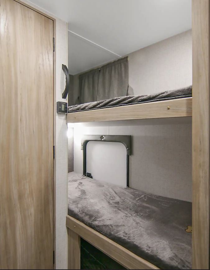 Cozy bunk beds in an RV rental, perfect for family adventures. Features plush gray bedding and individual lights.. Winnebago Minnie Winnie 2021