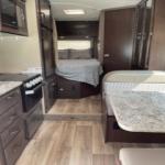 Spacious RV rental interior with kitchen, dining area, and bedroom. Ideal for road trip adventures.. Thor Motor Coach Freedom Elite 2019