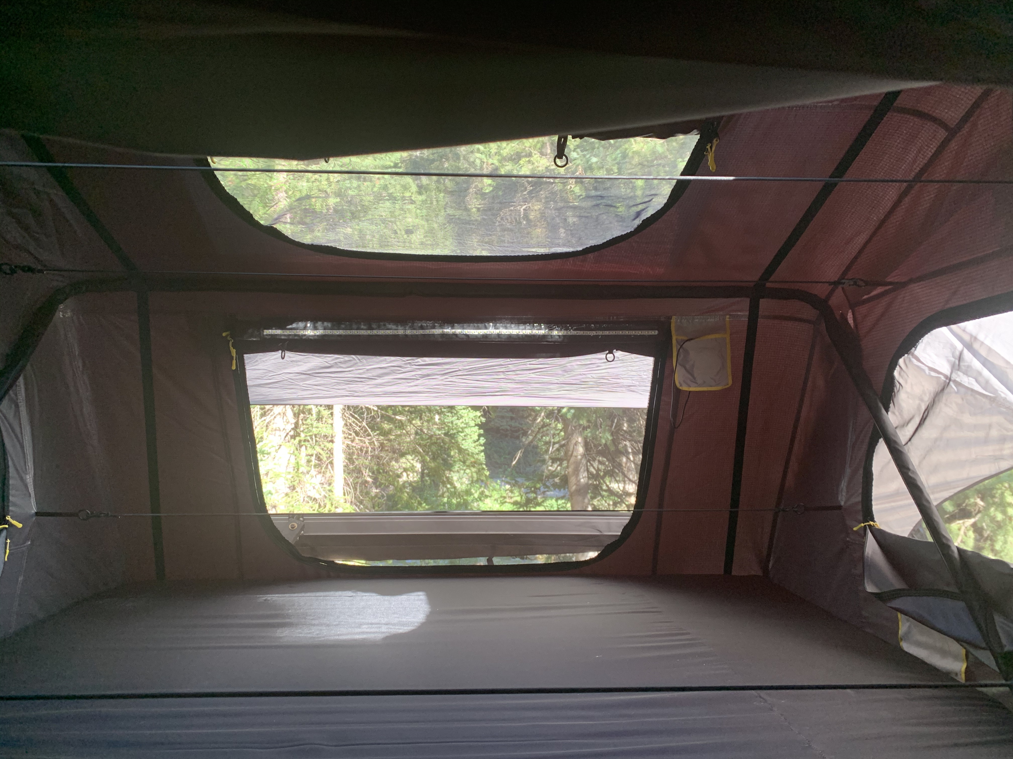Interior of an RV rental rooftop tent. Enjoy nature views from this cozy camping setup with a comfy mattress.. Jeep Gladiator 2020