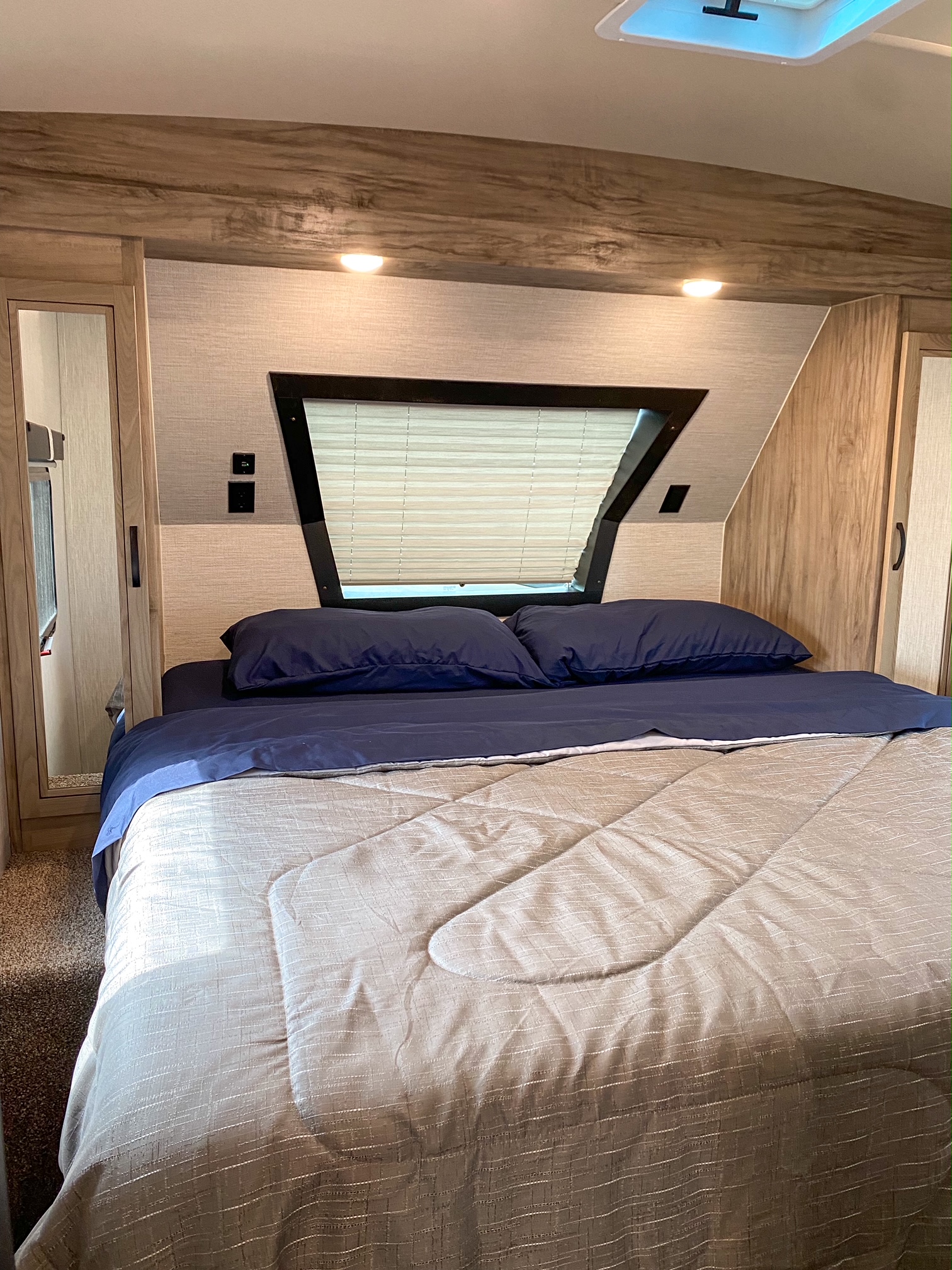 Serene RV rental bedroom featuring a blue-sheeted bed, window blinds, and built-in cabinetry.. Palomino Solaire Ultra Lite 2021
