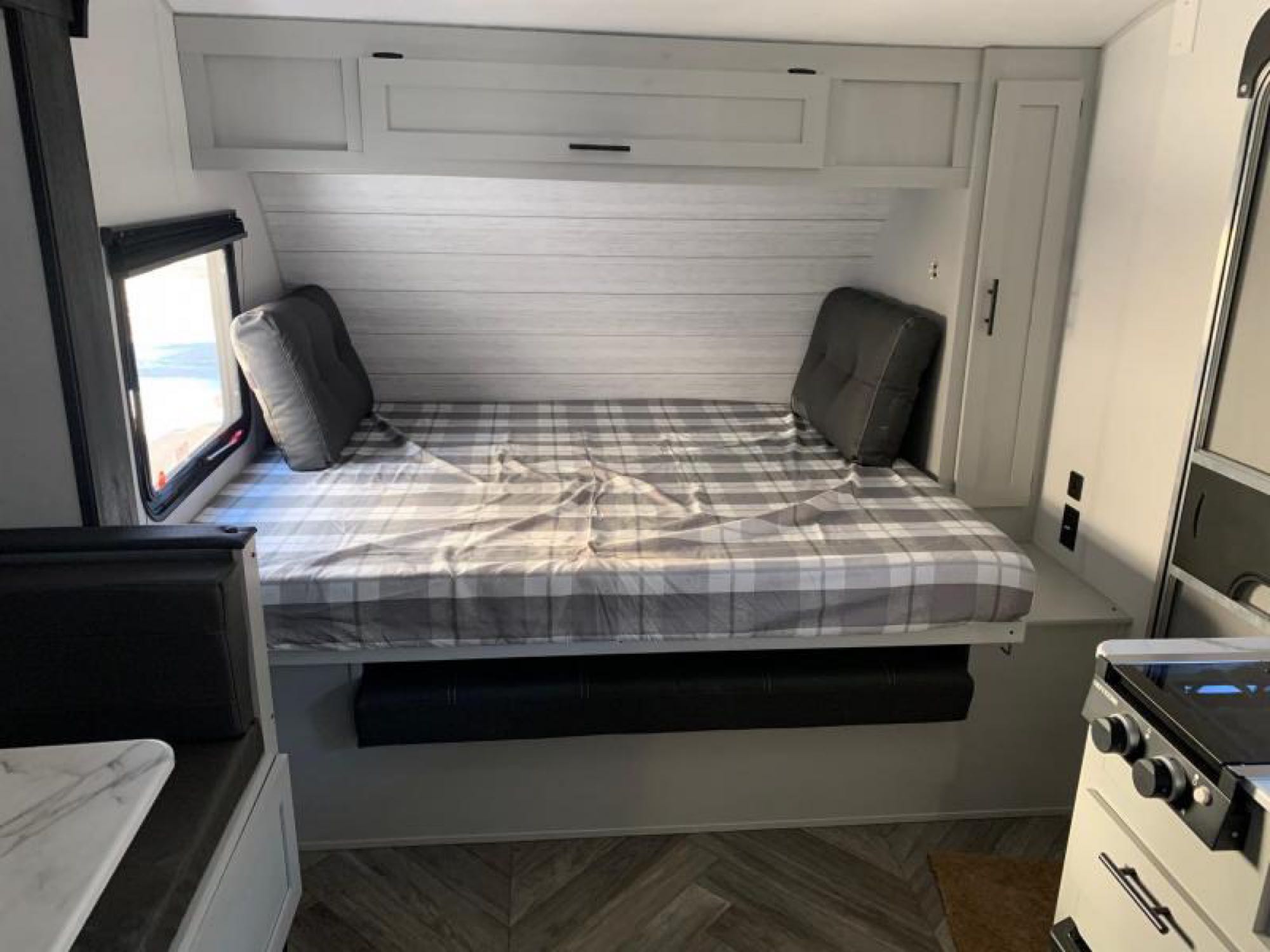 This RV rental offers a cozy bunk bed with plaid bedding, overhead storage, and compact kitchen space.. Forest River Salem 2021