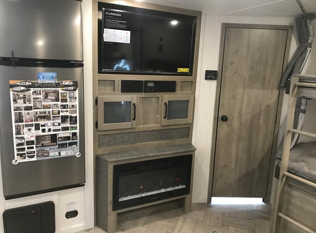 RV rental interior showcasing a modern living area with TV, electric fireplace, refrigerator, and bunk beds.. Forest River Palomino Puma 2021
