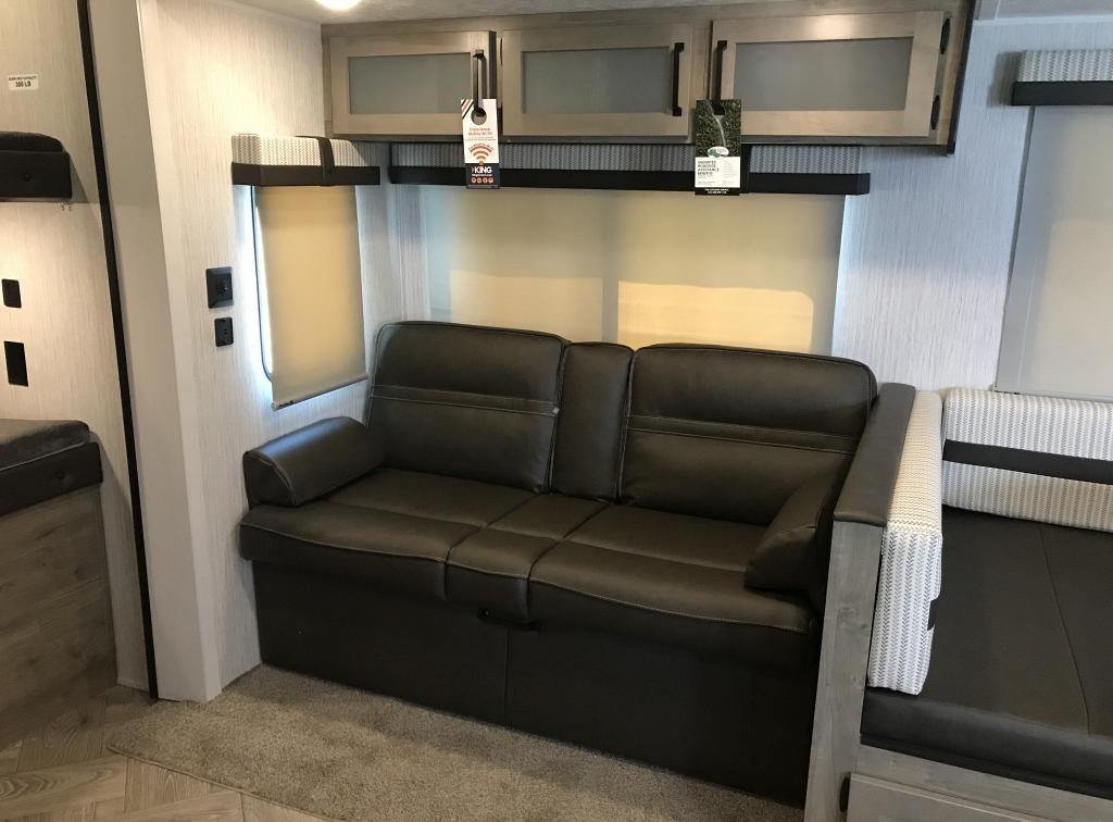 Modern RV rental interior with a comfortable dark sofa, dinette, and overhead cabinets for storage.. Forest River Palomino Puma 2021