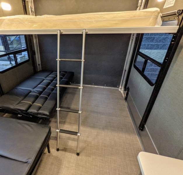 Spacious RV rental interior featuring an upper bunk bed with ladder and a lower convertible sofa for flexible sleeping.. Aluminum Trailer Company 2816 2021