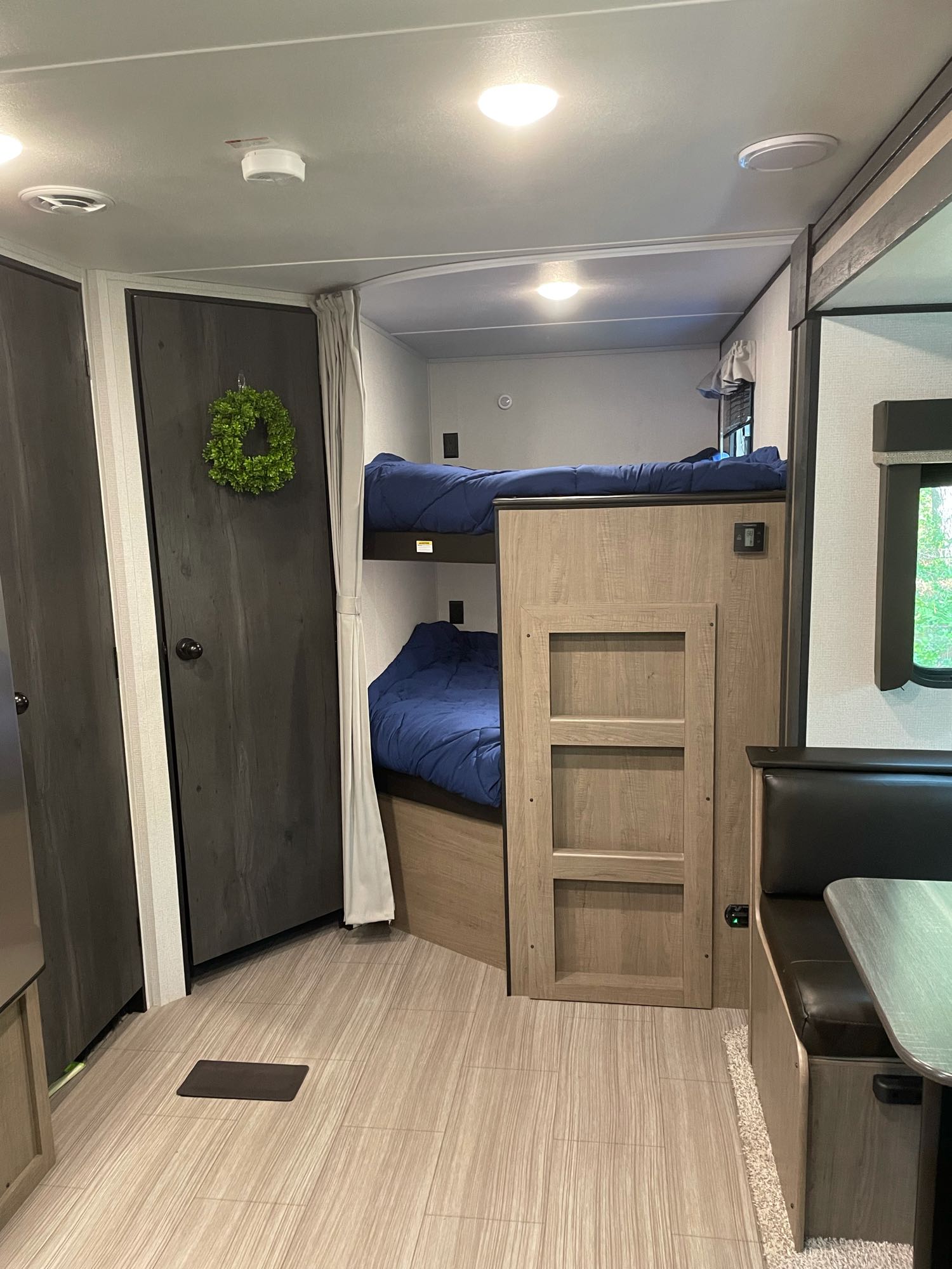 Inside an RV rental: view of neat bunk beds, compact dining area, and modern wood-look interior for comfortable travels.. Keystone Hideout 2021