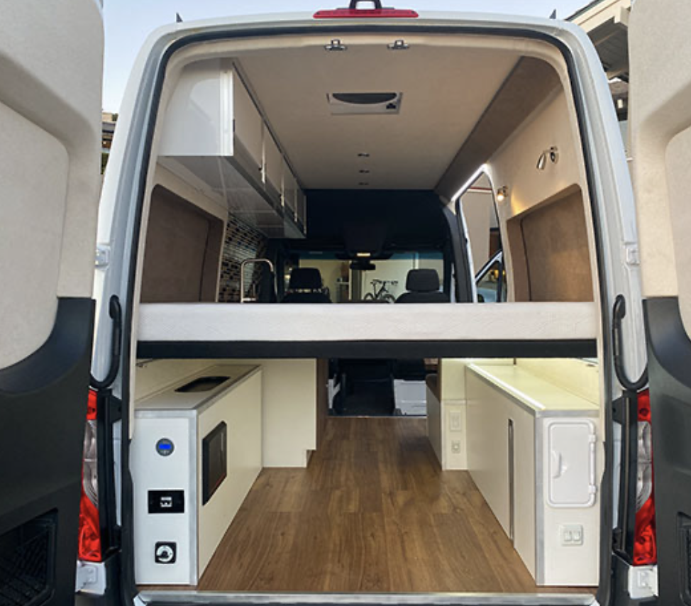 Spacious RV rental interior with a raised bed, kitchen, and ample storage, ready for adventure.. Mercedes-Benz Sprinter 2020